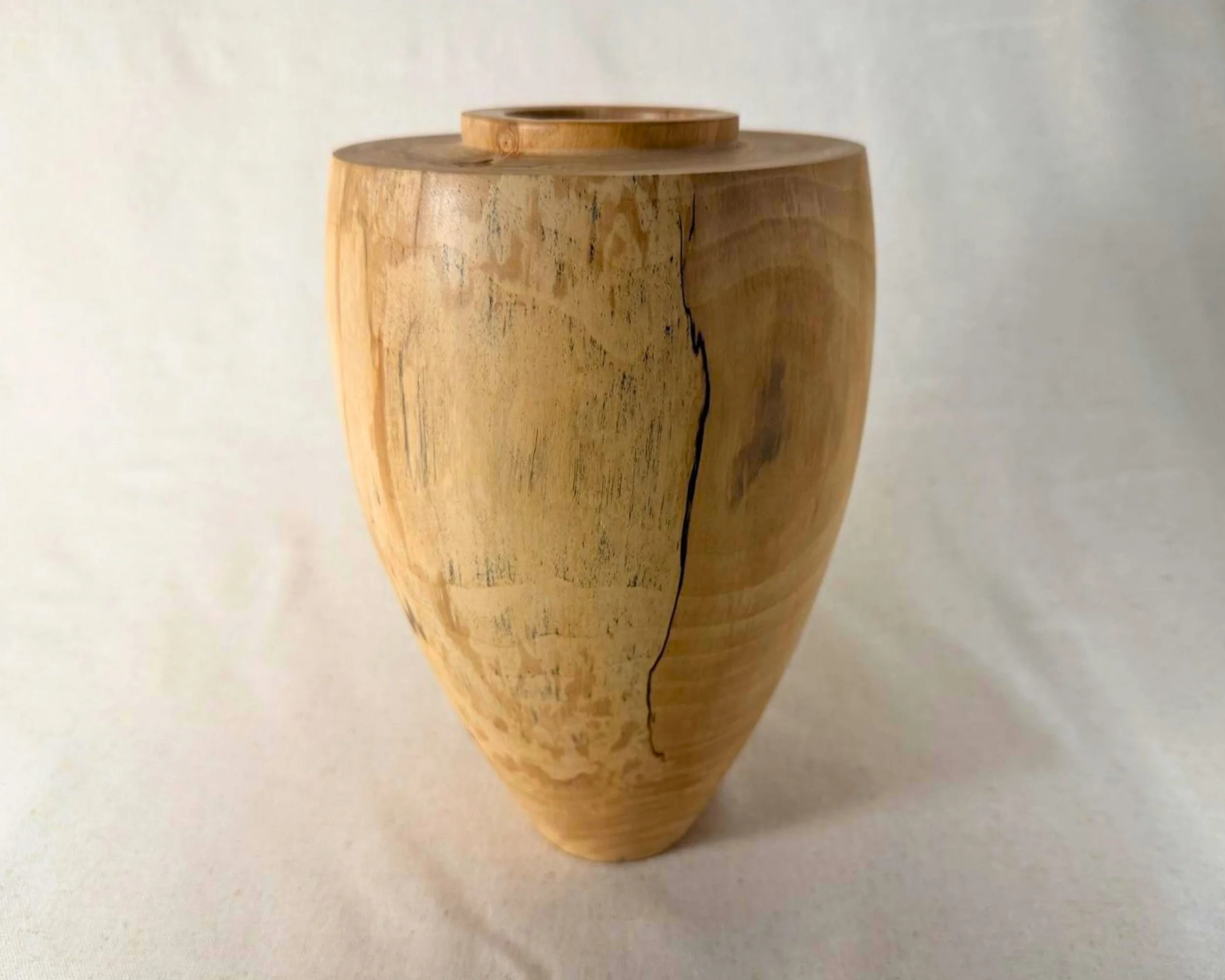 Spalted river birch vessel angled view highlighting a vertical black epoxy-filled fissure and soft tonal grain variation.