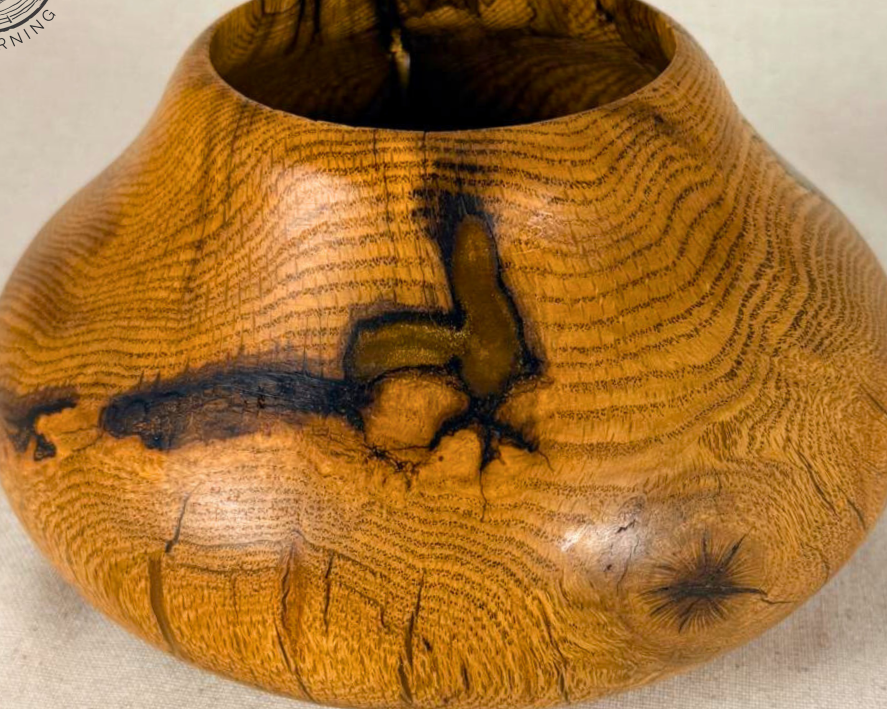 Wooden vase hand-turned from oak with natural grain patterns and inclusions filled with a neutral epoxy, sitting on a neutral surface.