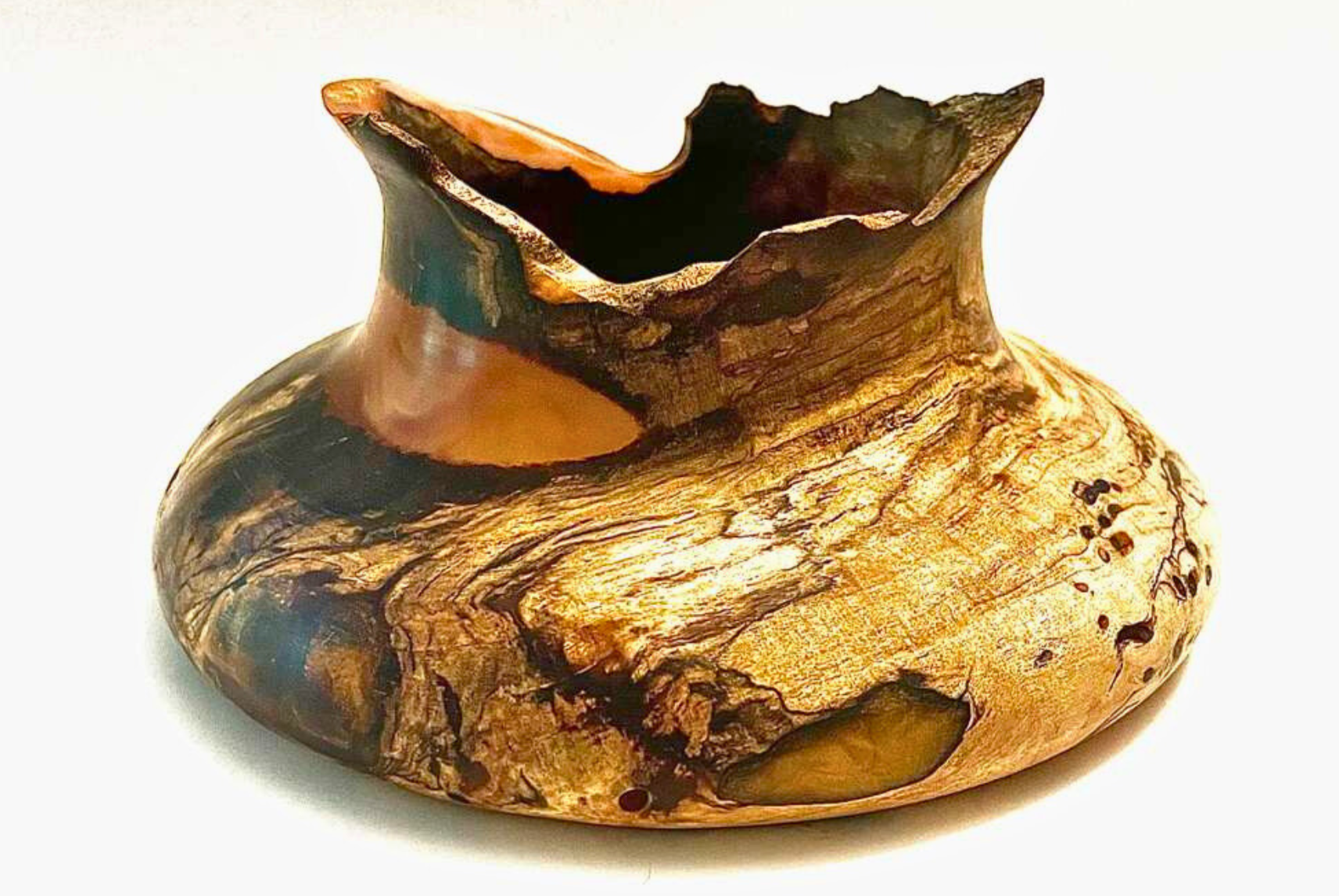 Wooden art sculpture carved from a single piece of wood, featuring a rounded base with an uneven, textured top edge.