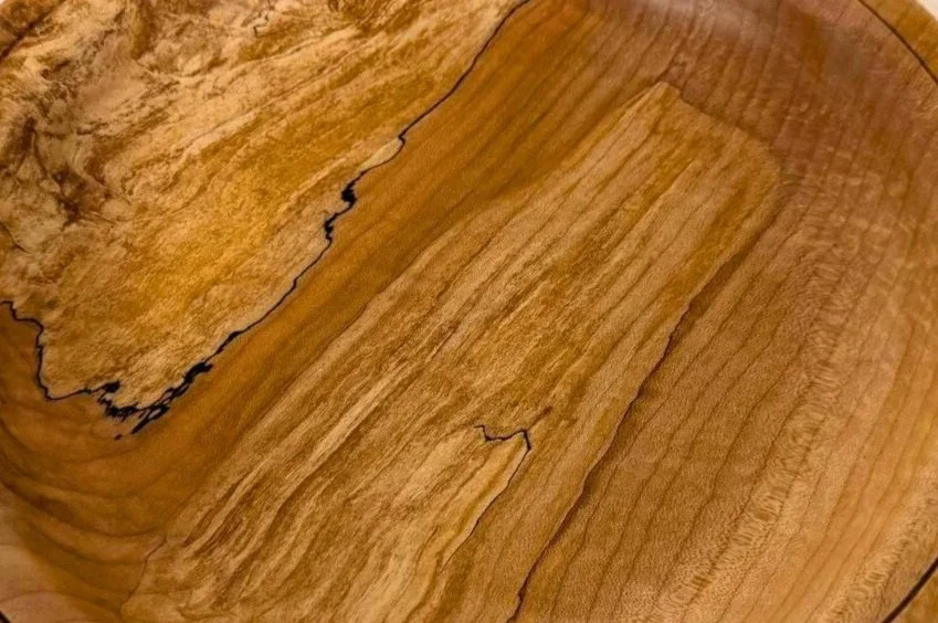 Close-up of a polished wooden surface with natural wood grain patterns and a dark edge along one side.