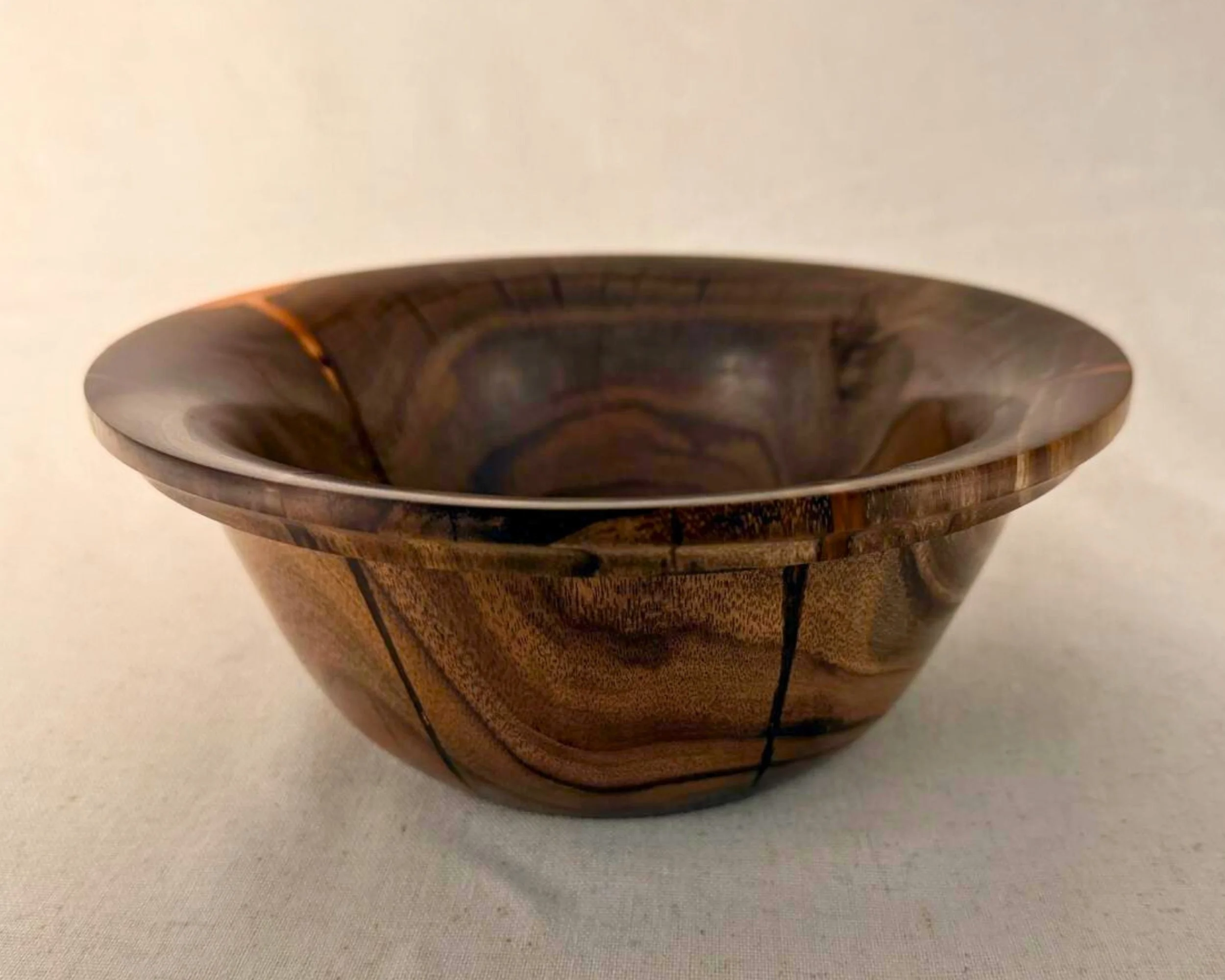 Primary hero image of a claro walnut bowl with bold red epoxy filling natural voids and highlighting rim areas.