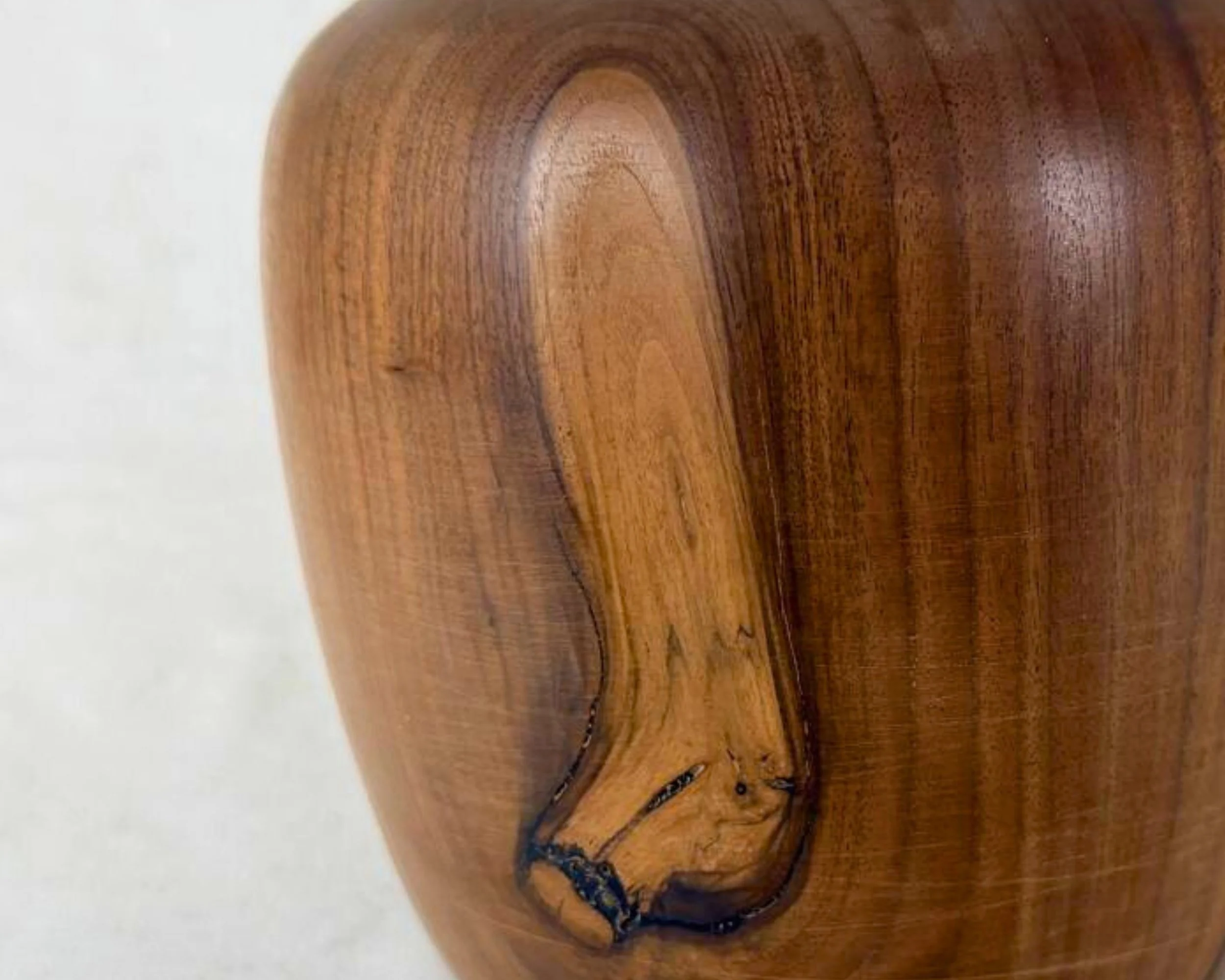 Close-up of walnut grain showing a natural void area with black epoxy fill and dark vein-like contrast.