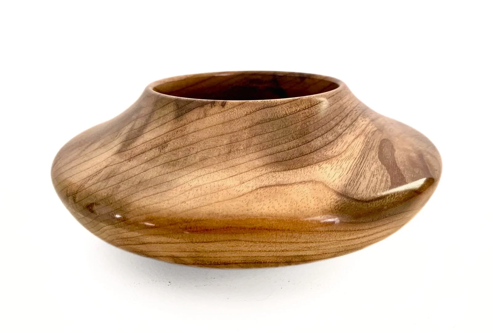 A smooth woodturned vessel, polished surface, showcasing the natural wood grain, placed on a white background.