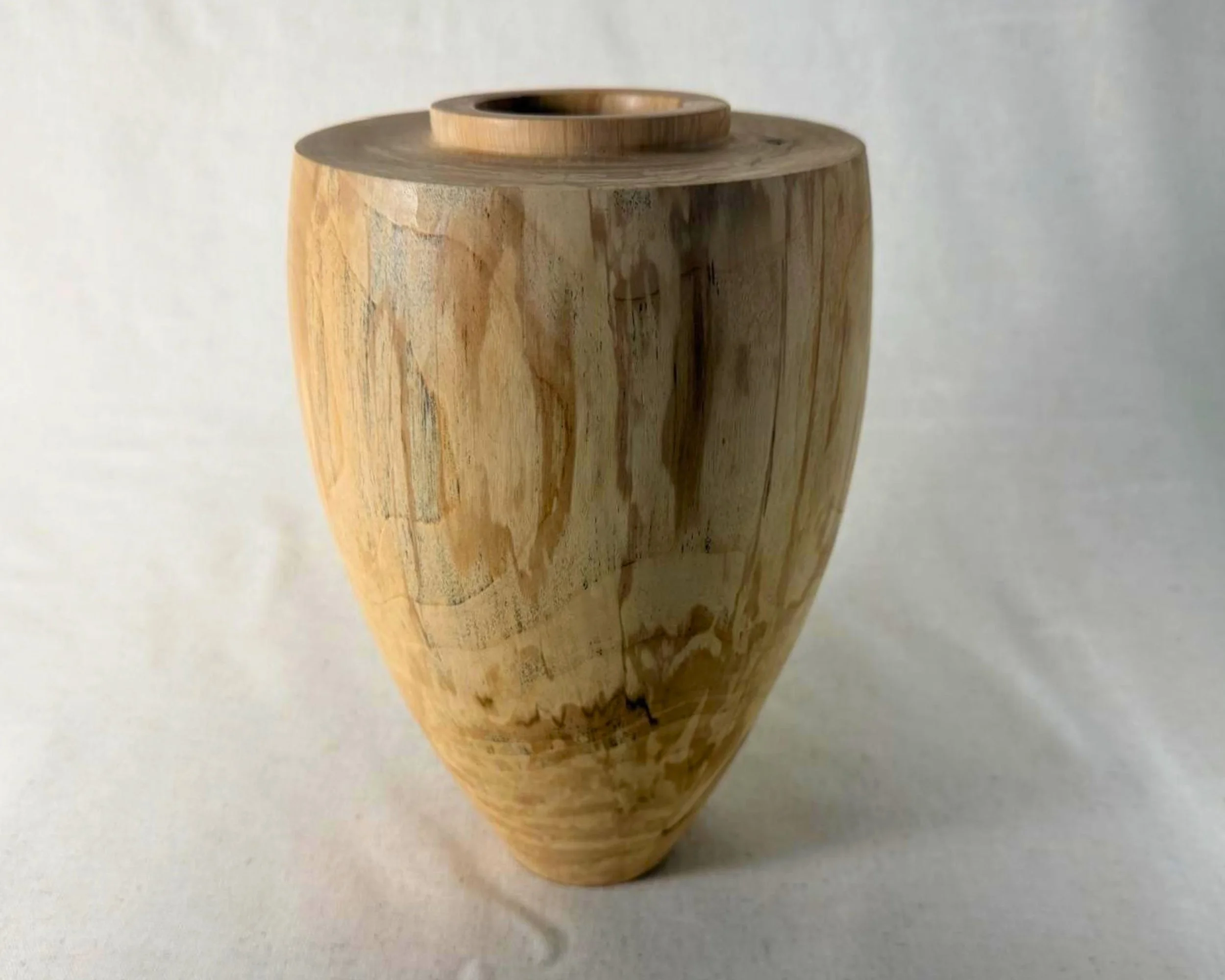Spalted river birch vessel with tall tapered form, subtle black epoxy-filled voids, and a small circular opening.