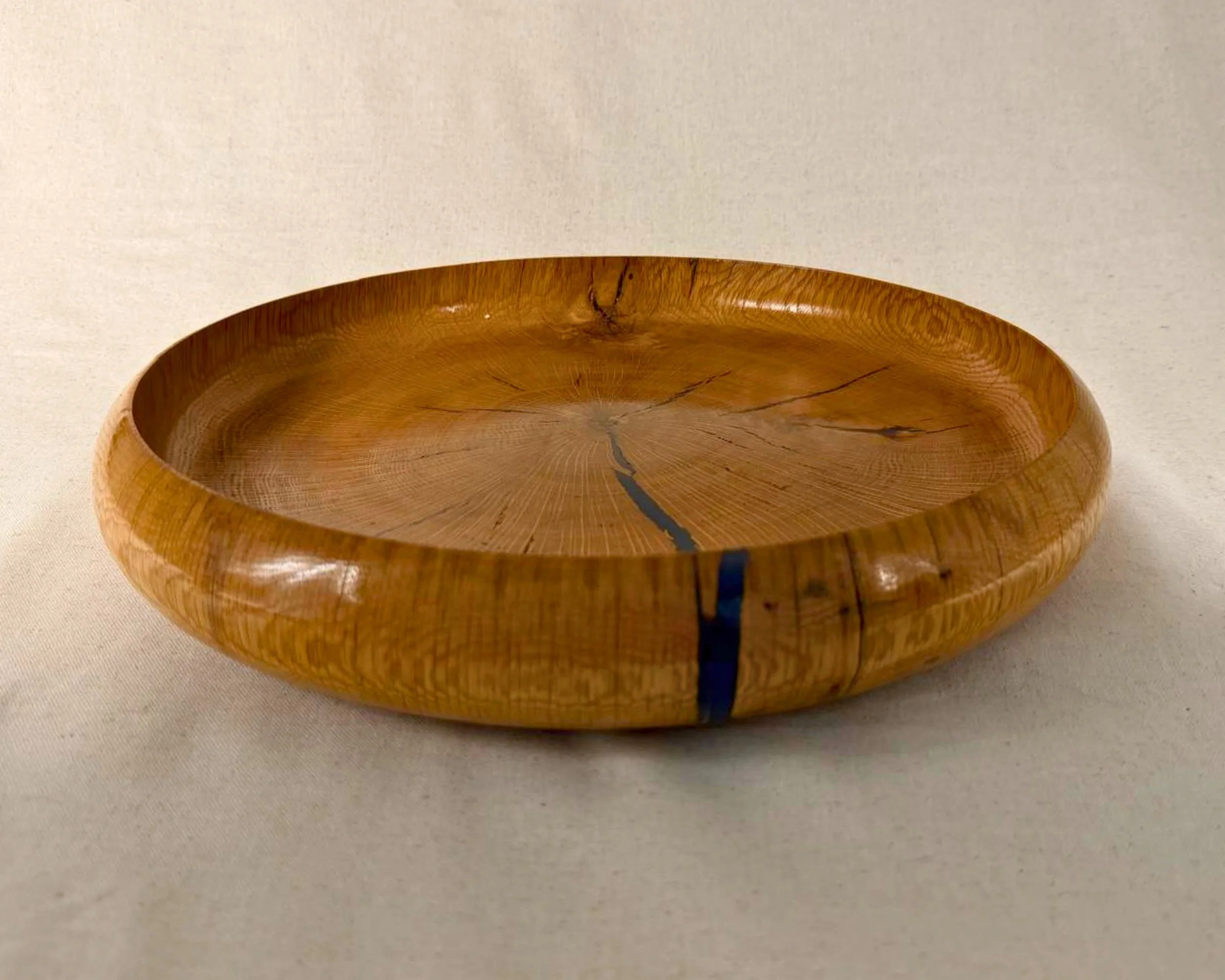 Reclaimed oak platter with dark blue epoxy accents shown at an angle on a neutral background, glossy finish.