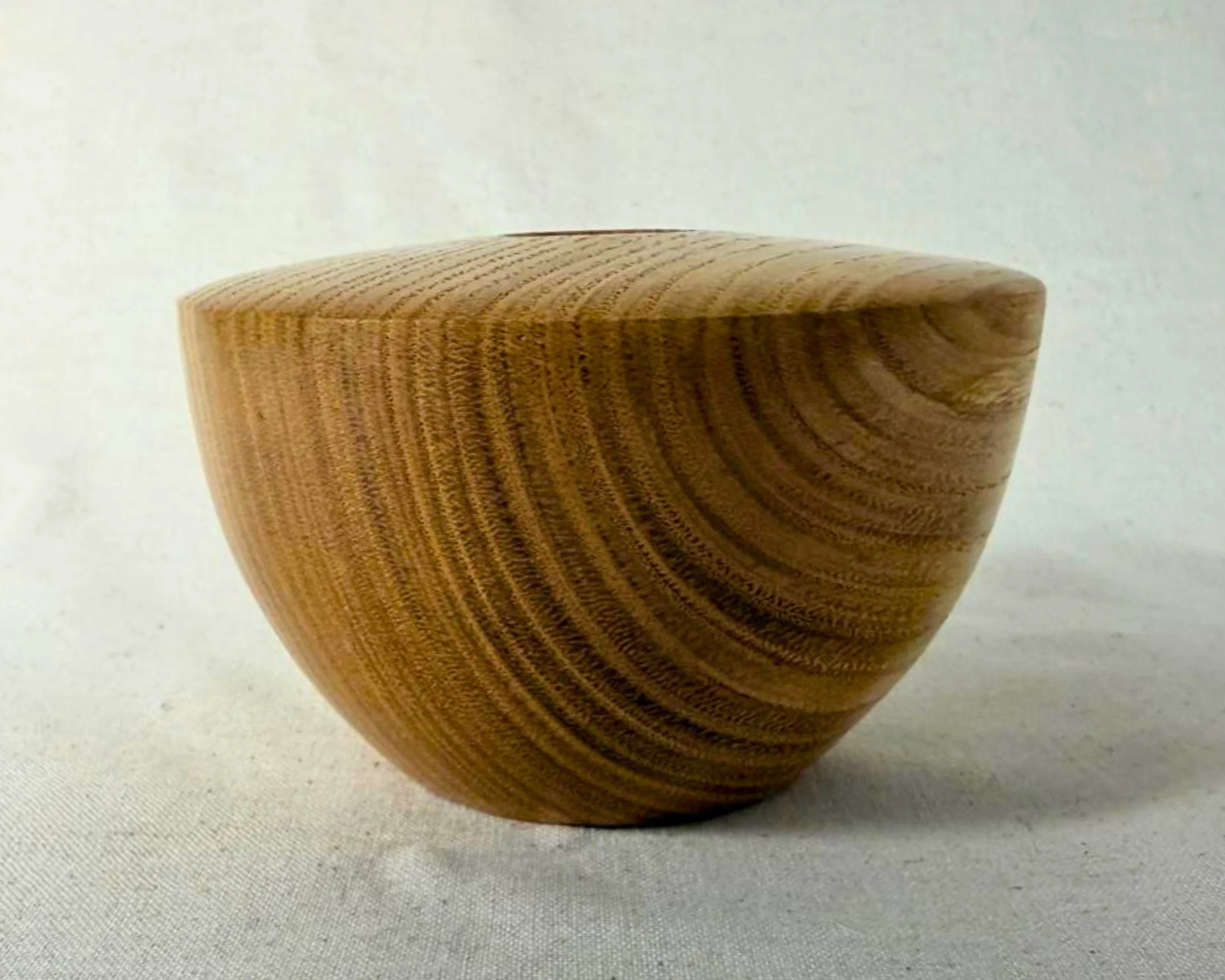 Upright view of the oak hollow form emphasizing the sculptural silhouette and grain movement.