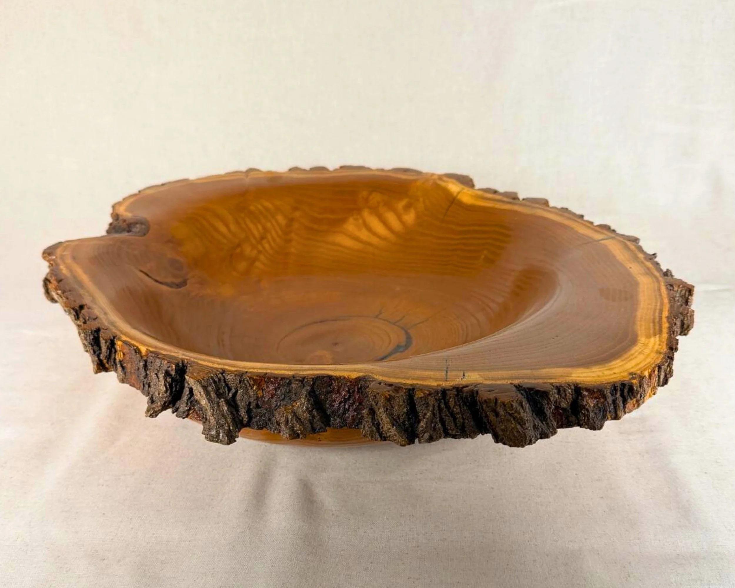 Mulberry live-edge bowl, angled view showing warm amber grain and natural bark rim