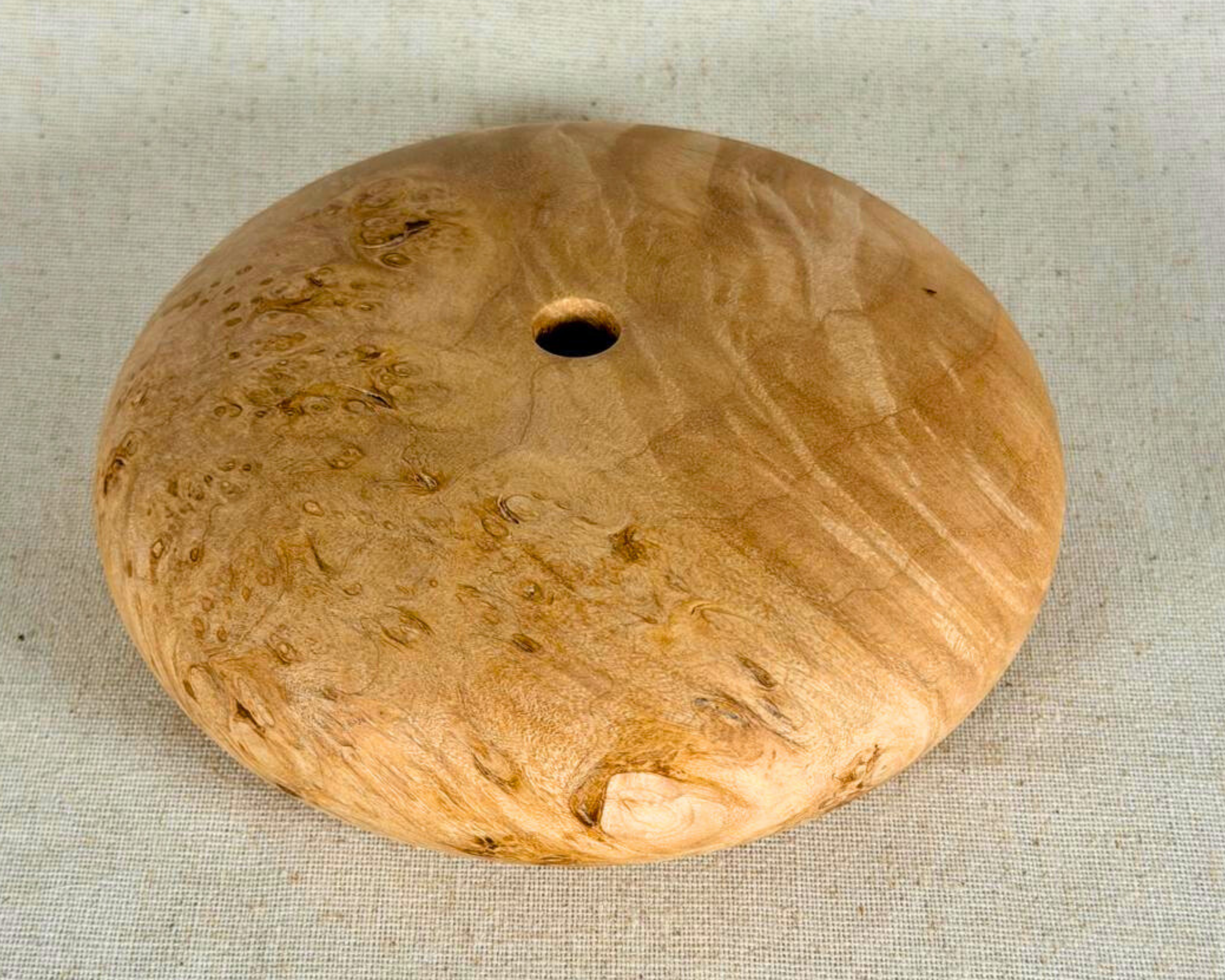 Angled hero view of the maple burl form highlighting the smooth surface, burl eyes, and low horizontal profile.