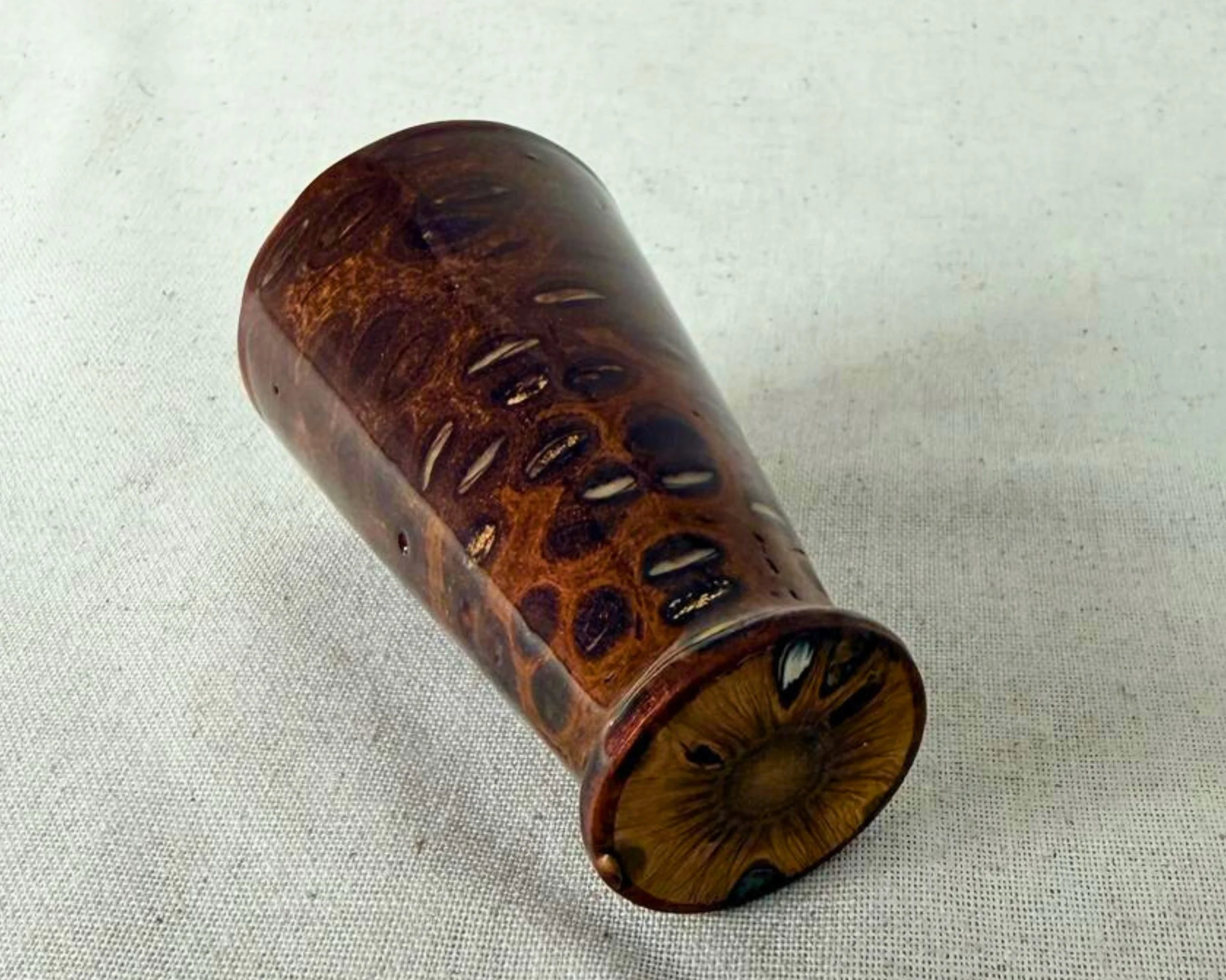 Banksia nut and red epoxy vessel resting on its side, showing the foot/base and the distribution of filled natural voids.