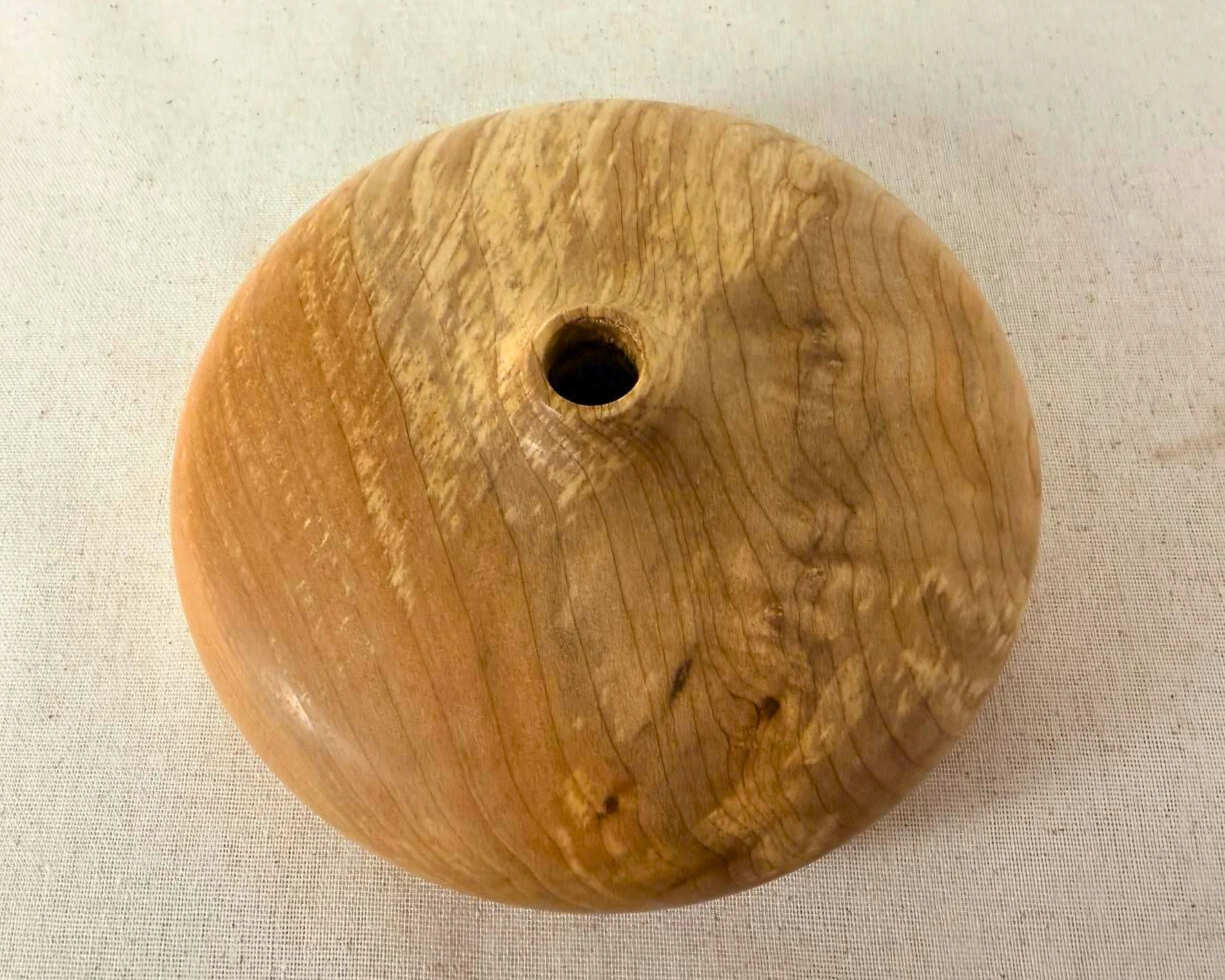 Overhead view of figured maple closed form vessel showing the opening and broad grain sweep across the surface.