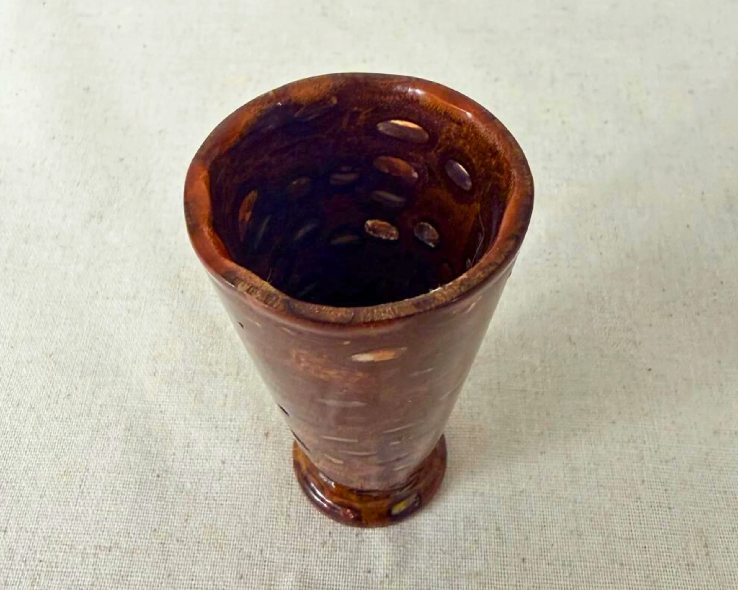 Angled top view into a banksia nut and red epoxy vessel, showing interior walls with filled voids and glossy surface.