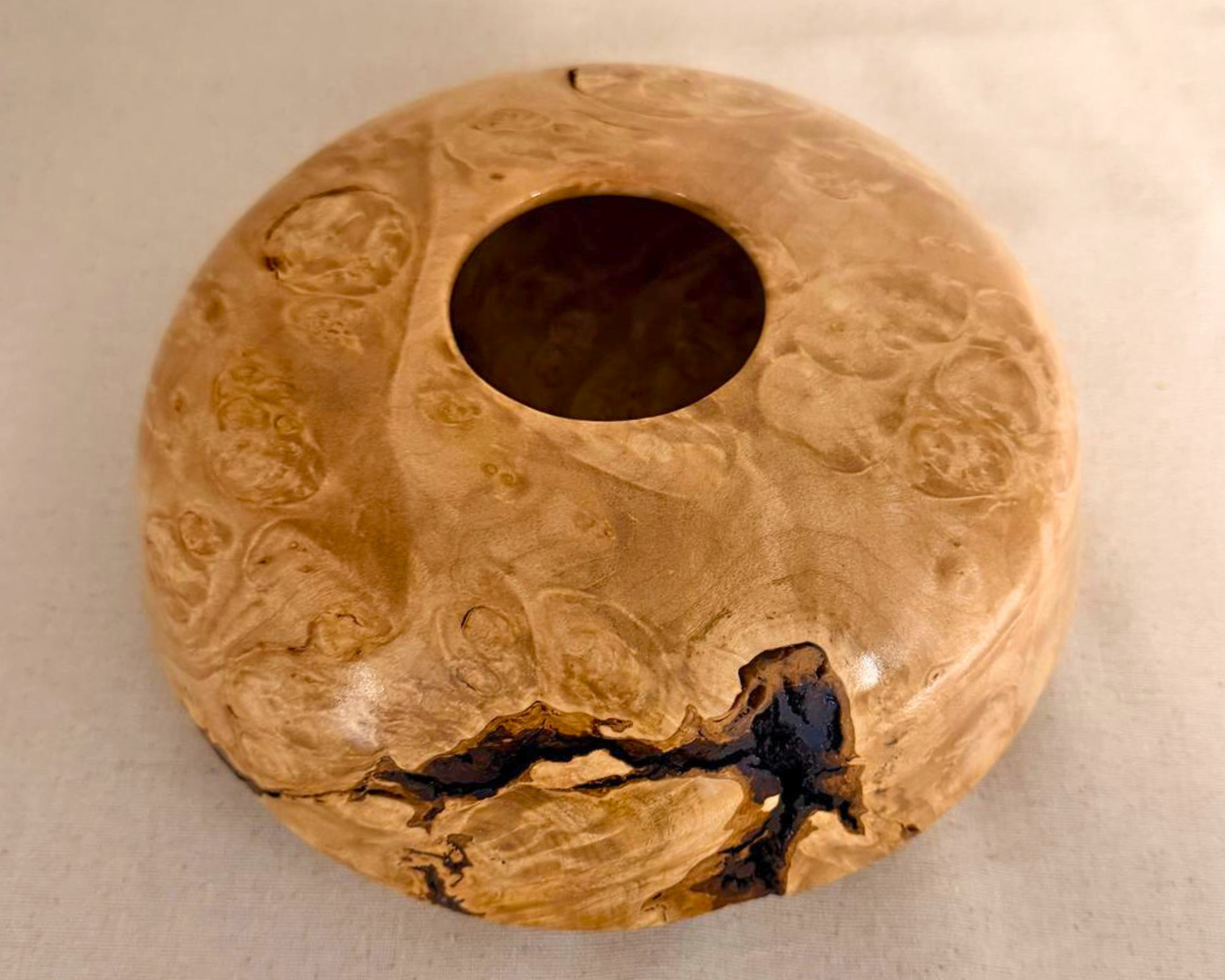 Top view of the maple burl vessel with a 2.25-inch opening, circular grain movement, and a prominent dark natural void near the rim.
