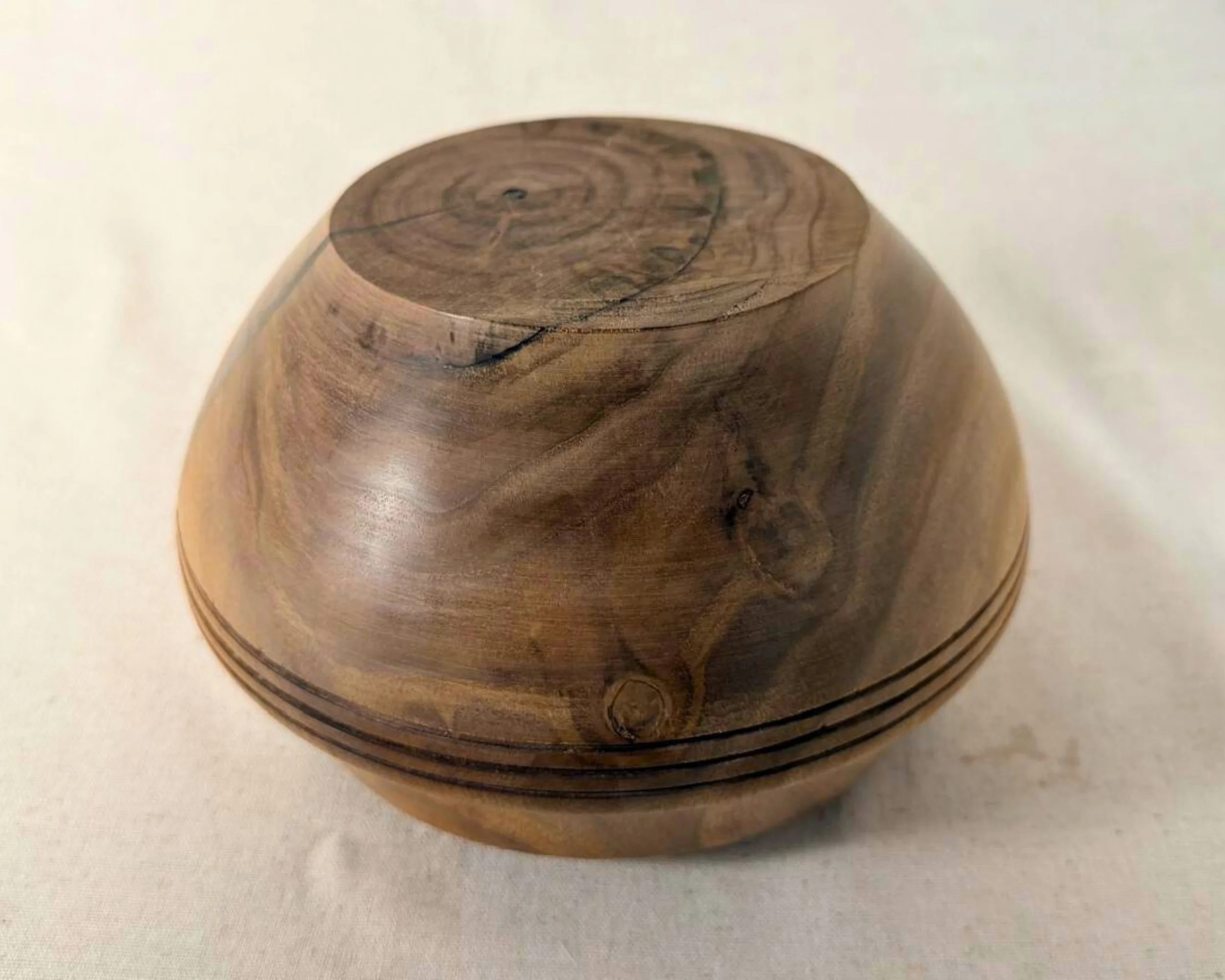 Bottom view of walnut bowl showing turned base, walnut grain pattern, and subtle natural markings.