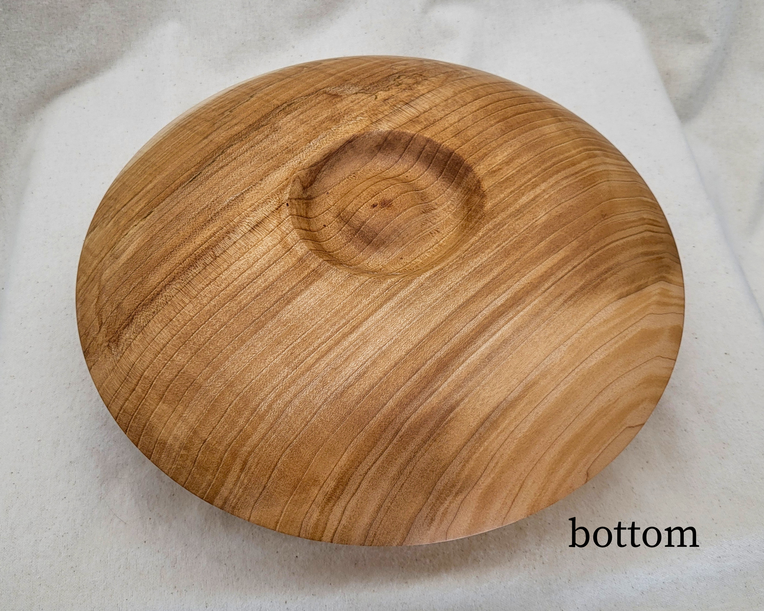 Underside of a curly maple closed-form hollow vessel by Treverk Woodturning, revealing the gently recessed foot, soft matte satin finish, and continuous curly figure across the lower face of this one of a kind wood vessel.