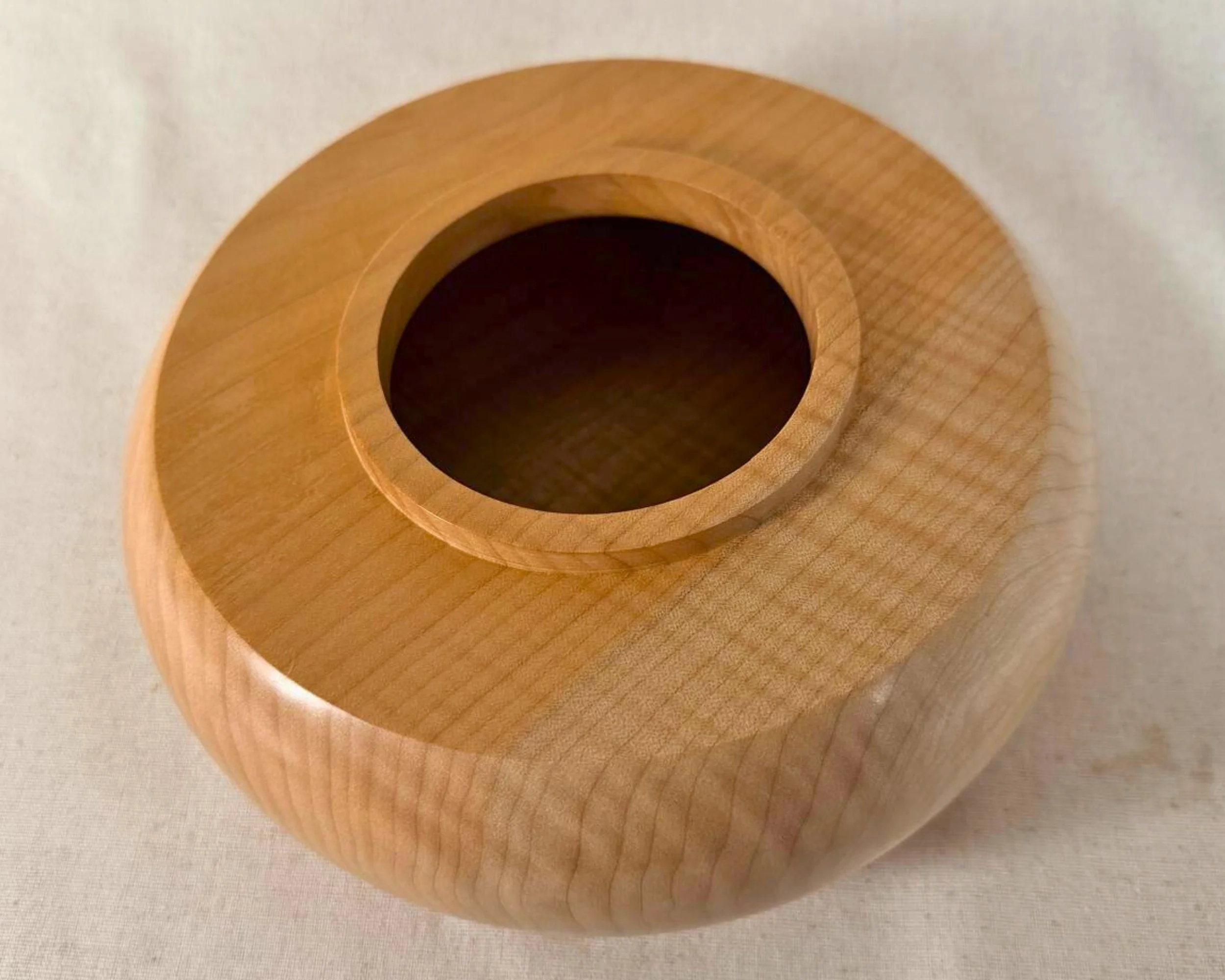 Top view of the maple closed form vessel showing the raised collar opening centered on a broad smooth top surface.