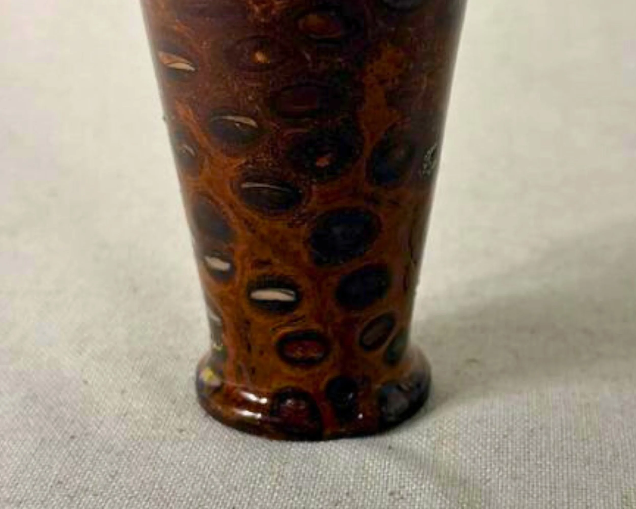 Close-up of banksia nut surface with red epoxy filling natural voids, showing glossy finish and varied translucency.