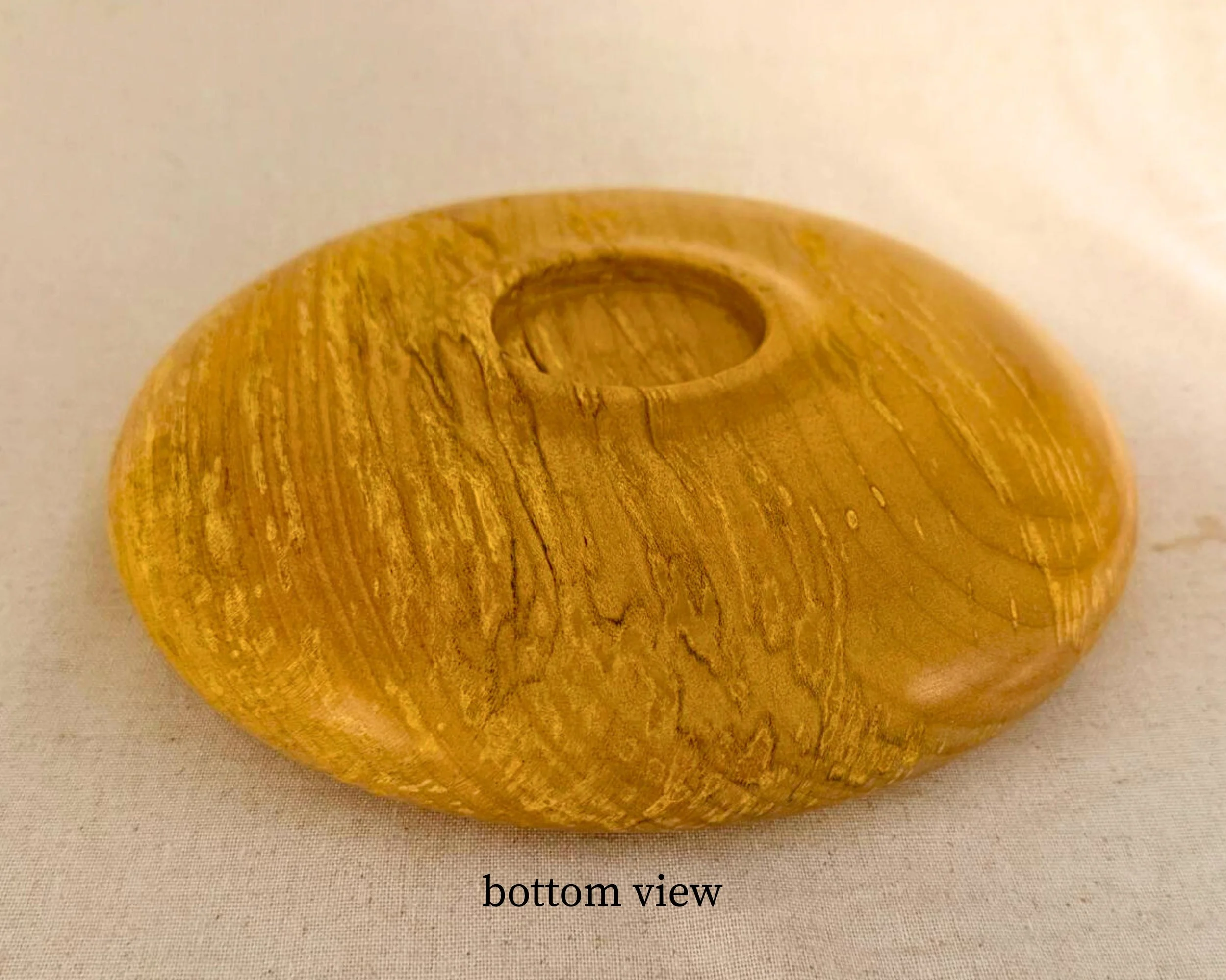 Bottom view of the hand-turned figured maple closed form vessel showing smooth base and continuous grain with satin finish.