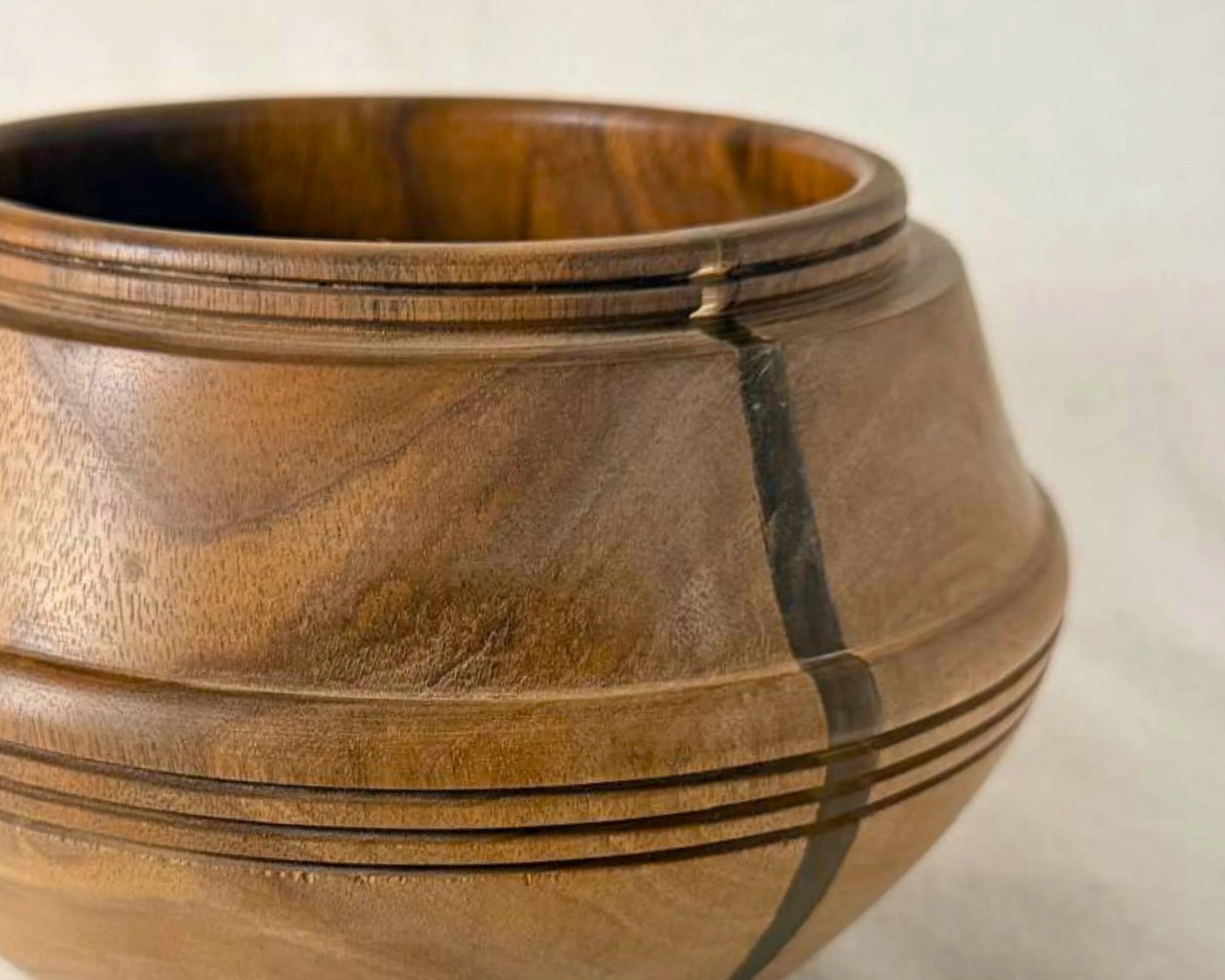 Close-up of walnut bowl banding detail and subtle grain variation with a neutral epoxy accent line.