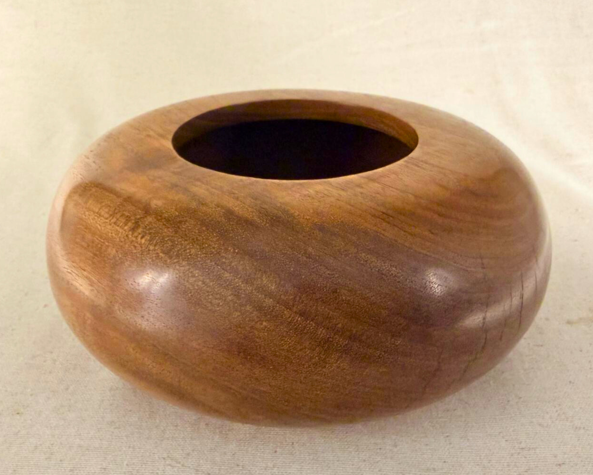 Top view of claro walnut closed form vessel showing wide circular opening and subtle grain movement in warm brown tones.