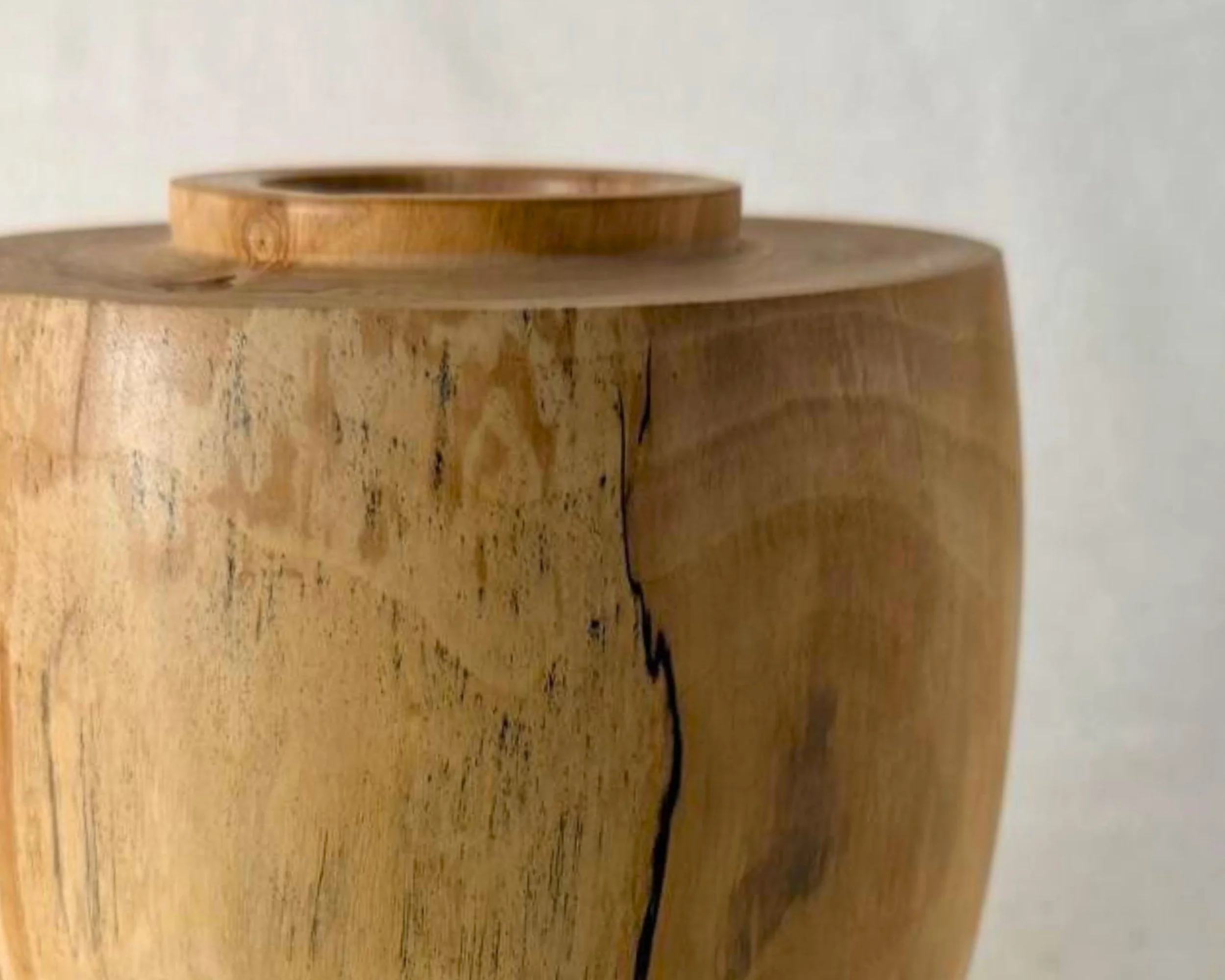 Close-up detail of black epoxy filling a narrow void in spalted river birch on the vessel’s side.