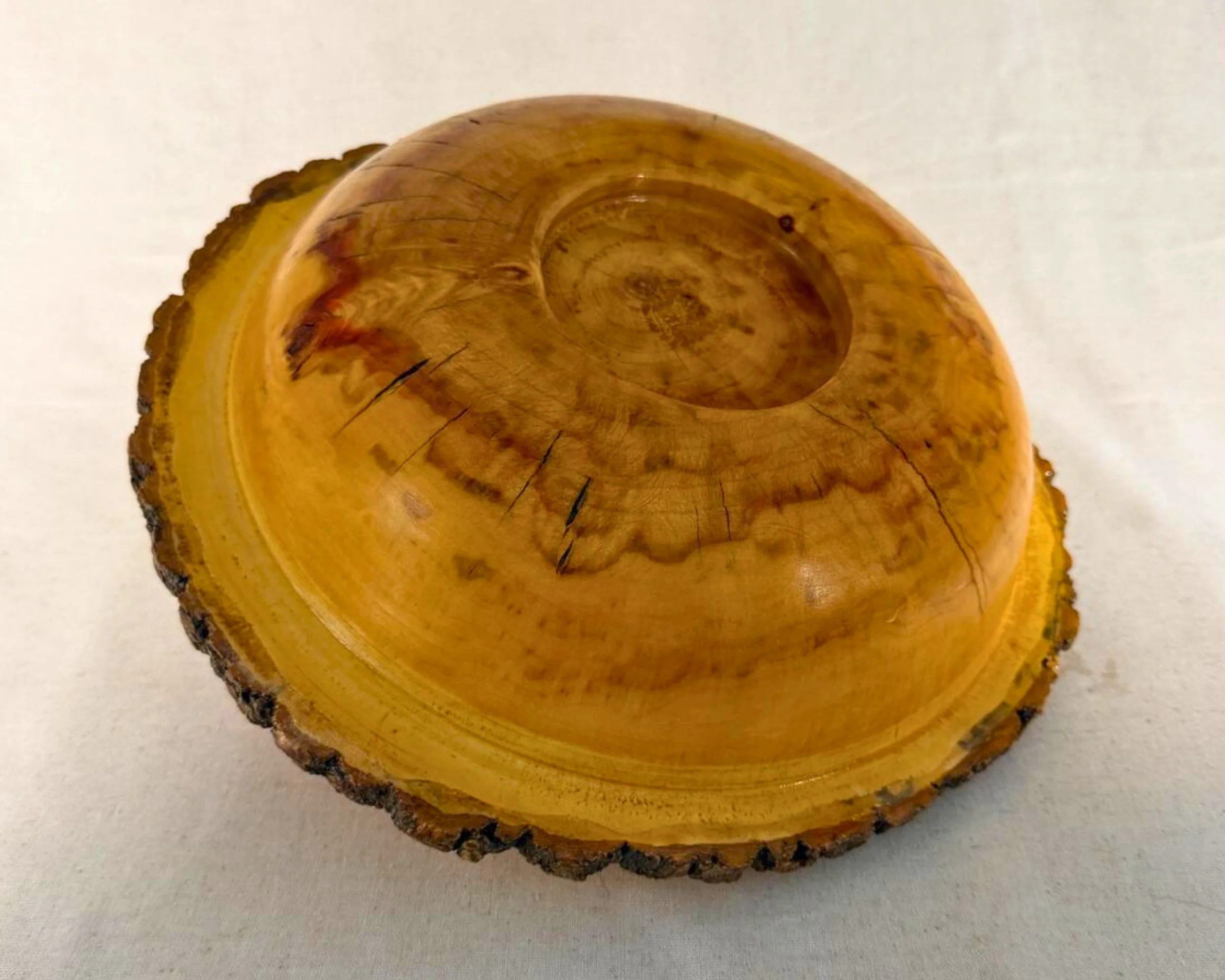Bottom view of reclaimed walnut live edge bowl showing turned base and grain pattern.