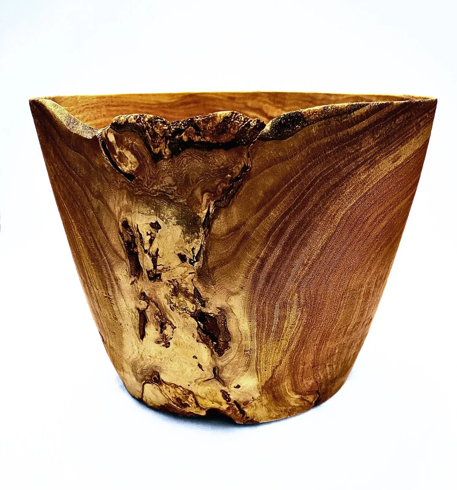 A handcrafted lathe-turned bowl with natural grain and some bark edges, isolated on white background.