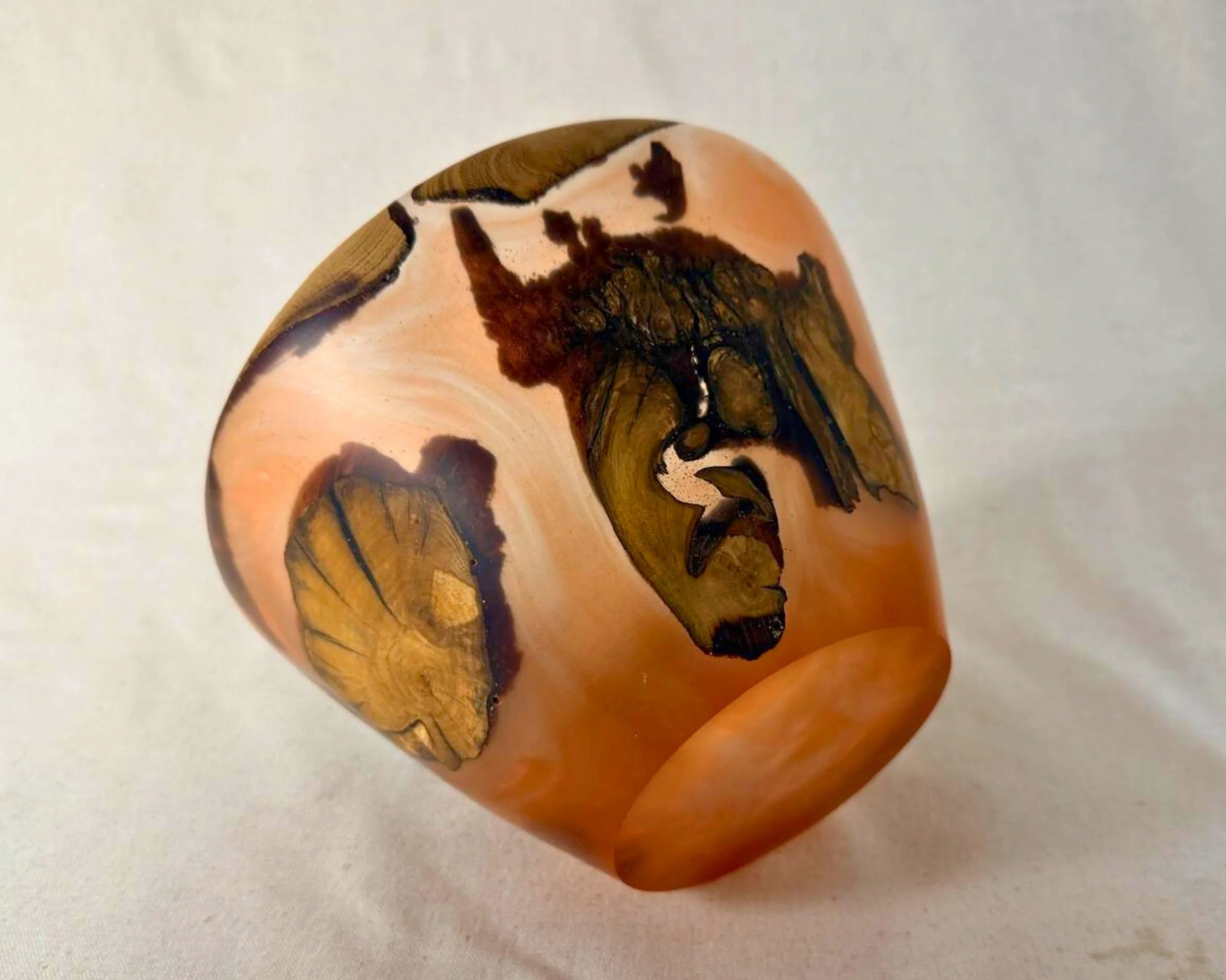 Bowl tipped on its side showing the exterior amber epoxy field with large embedded wood sections.