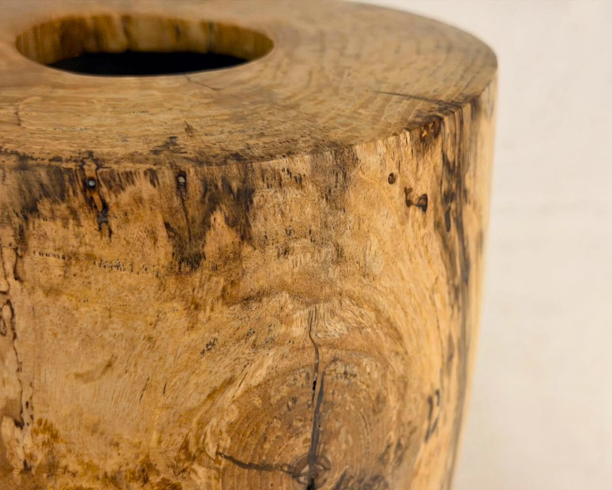 Close-up detail of maple grain and subtle spalting on the upper sidewall near the rim.