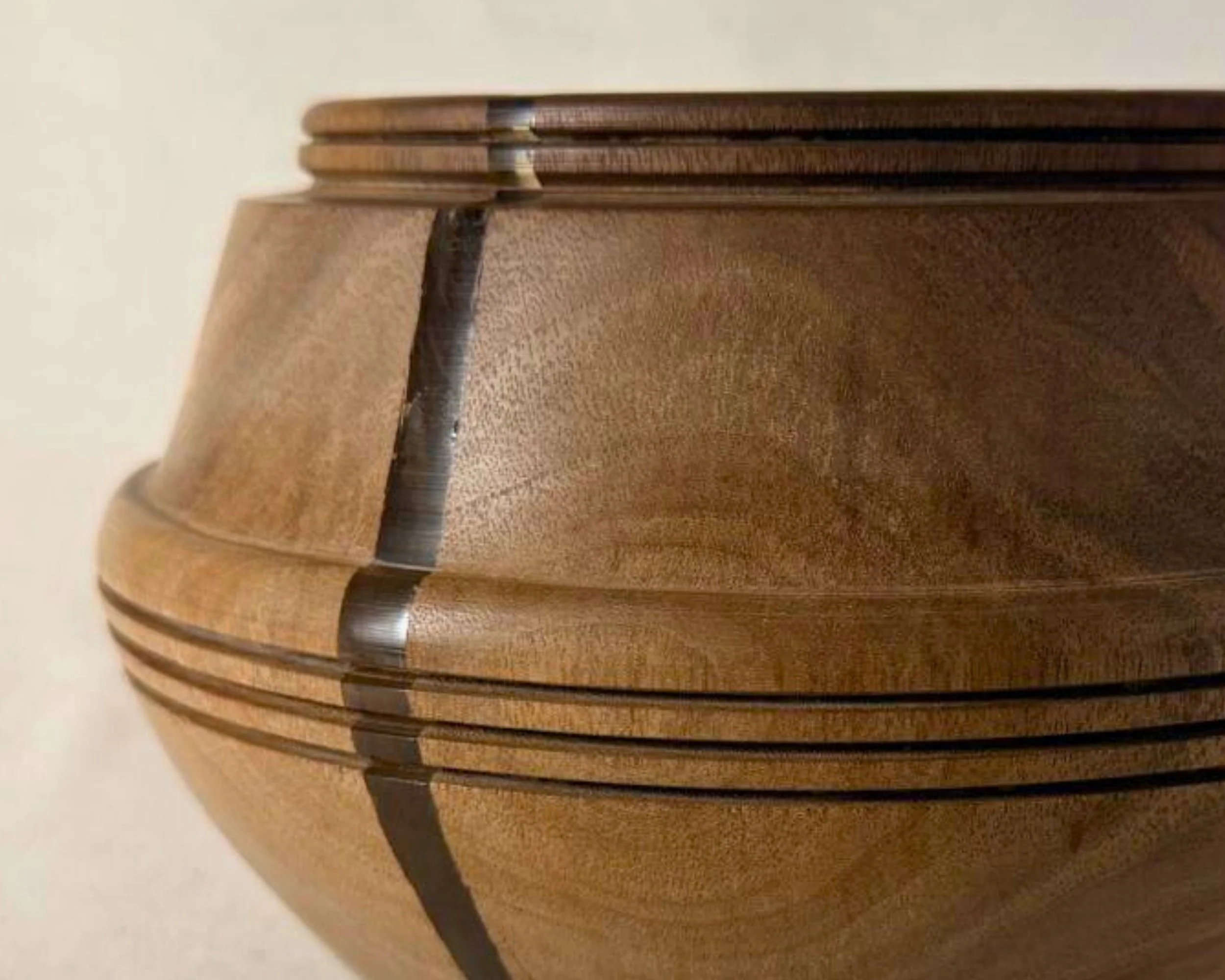 Close-up of walnut bowl showing the neutral epoxy accent line crossing the banded grooves near the rim.
