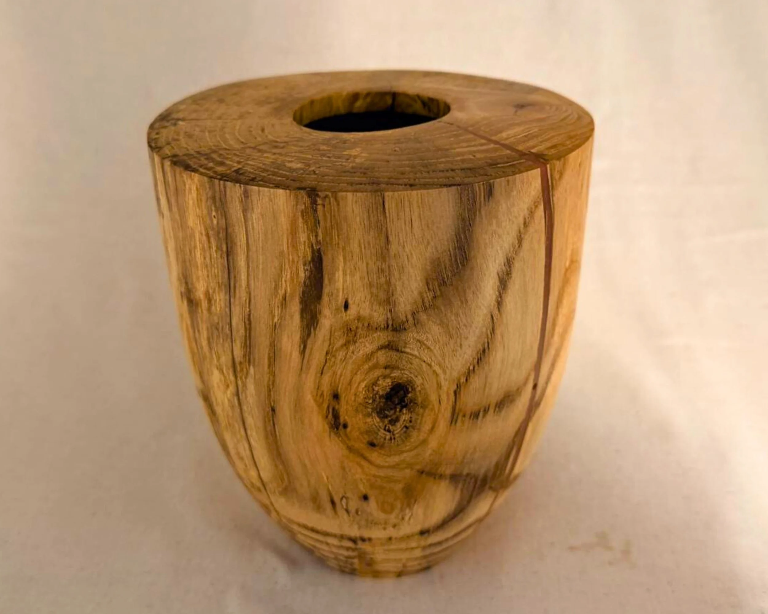 Maple vessel with flat top and centered opening, subtle spalting visible across the front face and rounded profile.