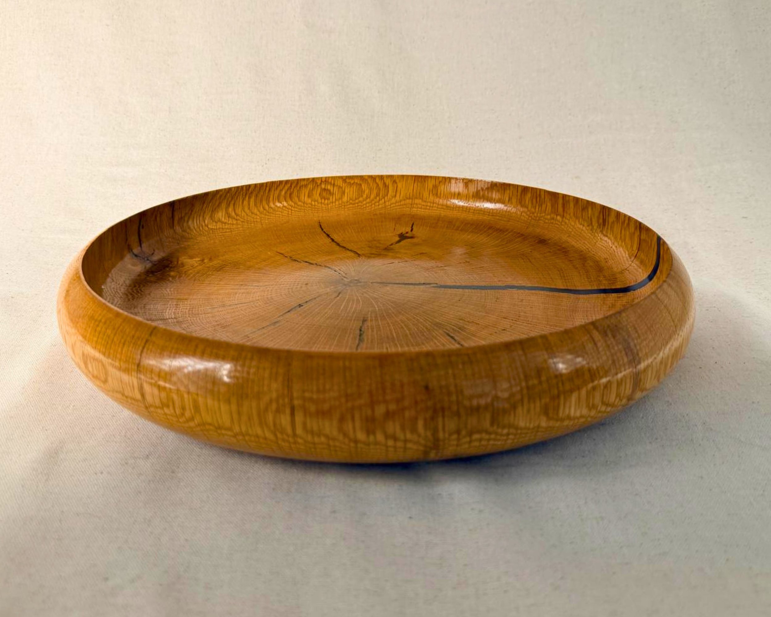 Hero image of a reclaimed oak platter with dark blue epoxy filling natural voids, glossy finish, wide shallow form.