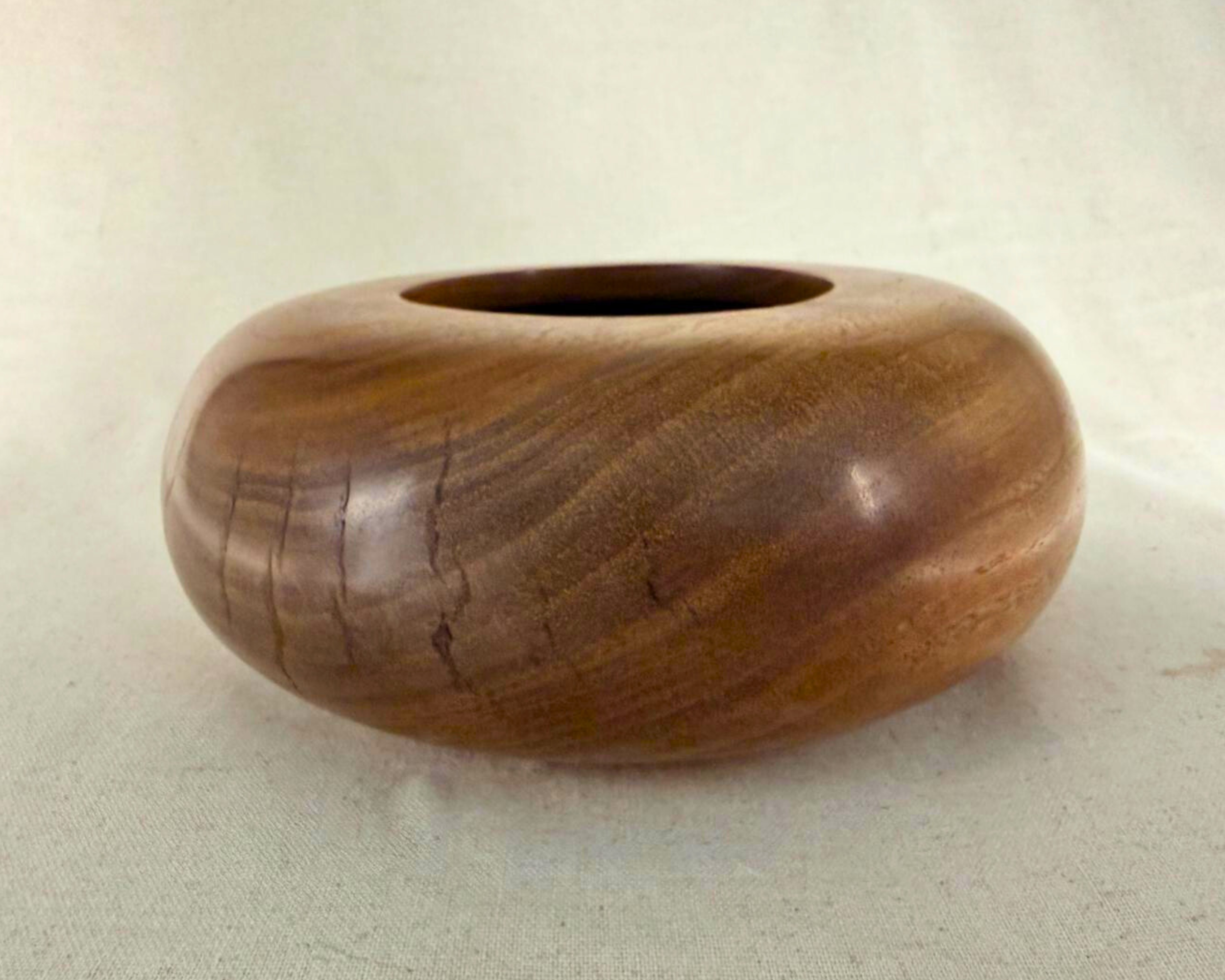 Side profile of claro walnut closed form highlighting the low, wide proportions and smooth continuous curve around the body.