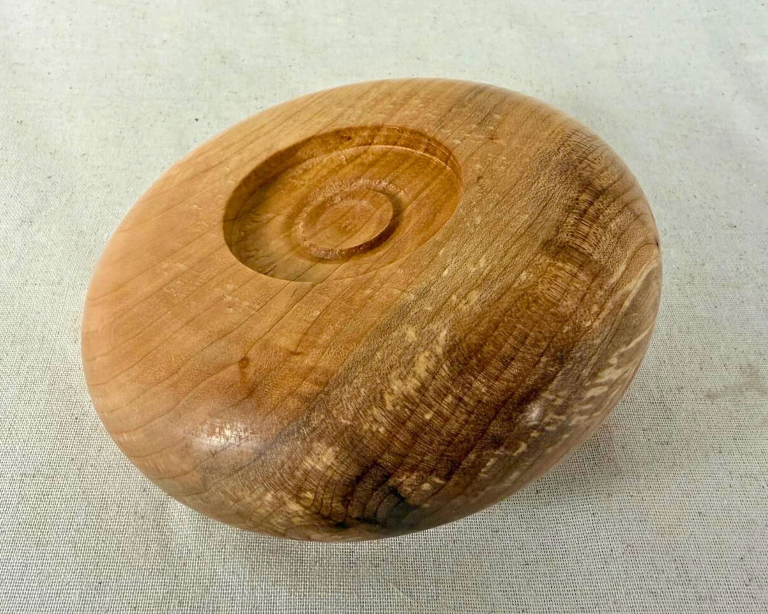 Bottom view of figured maple closed form vessel showing the turned foot and circular grain pattern.