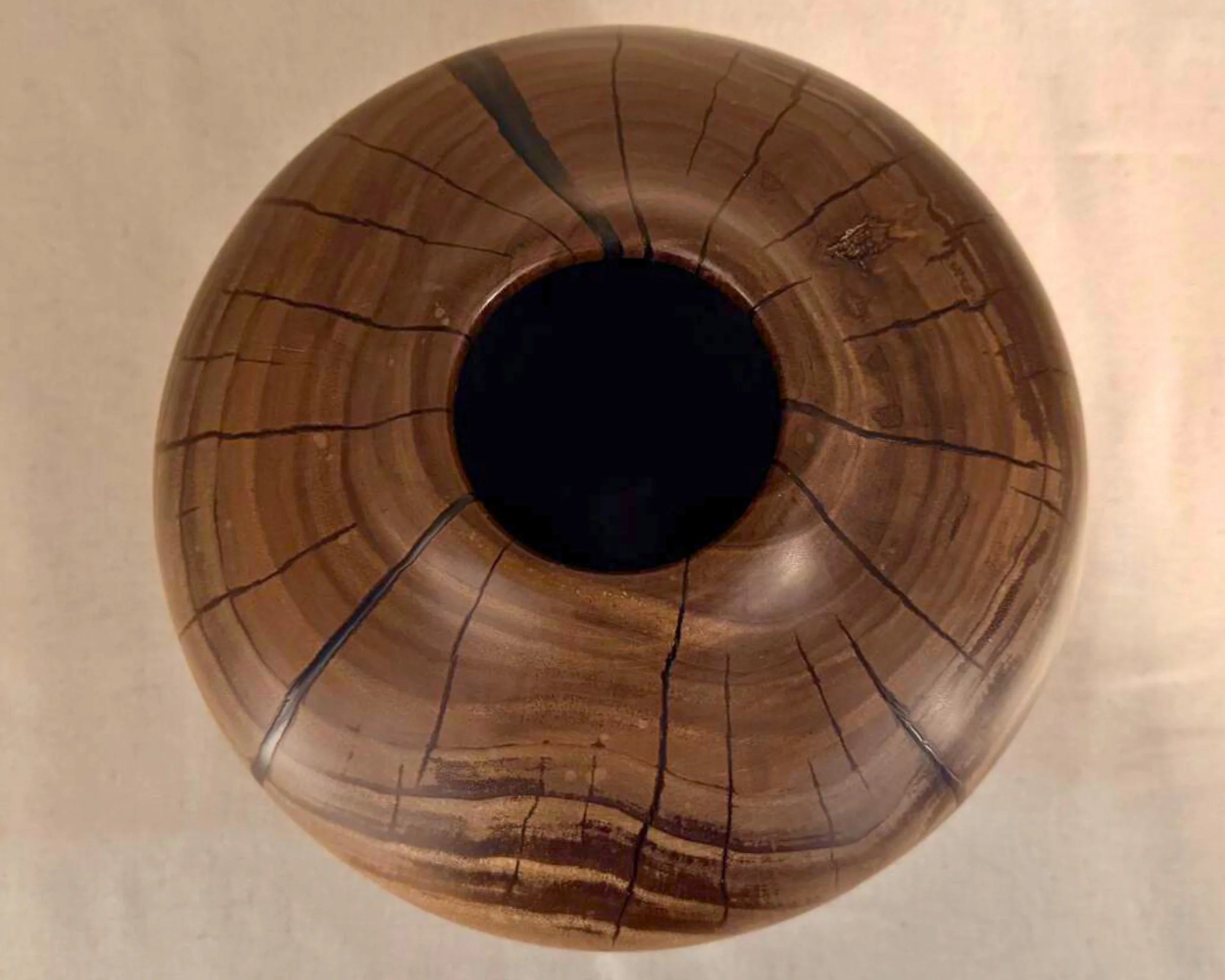 Top-down view of walnut vessel showing circular grain rings around the opening and dark epoxy vein lines radiating outward.
