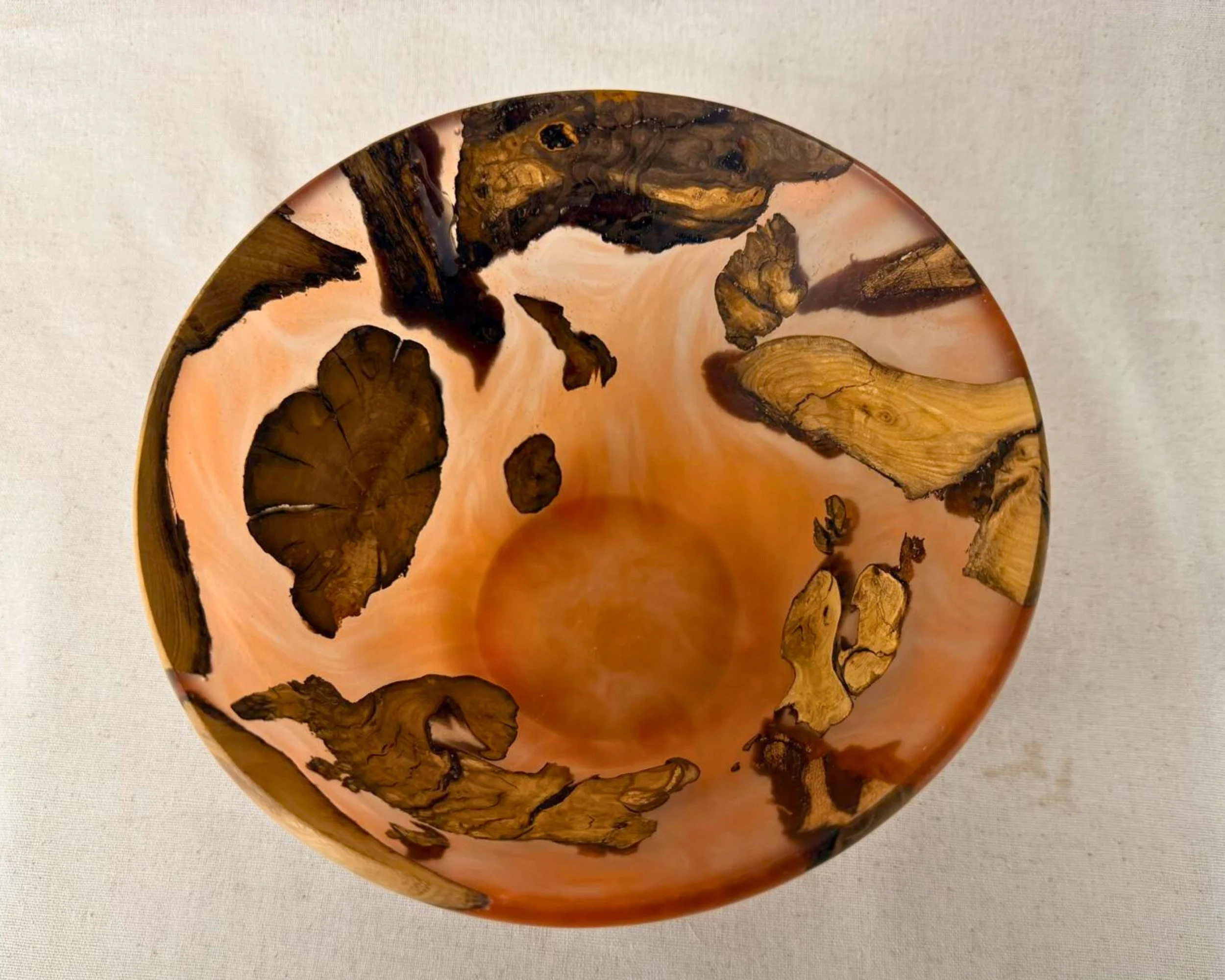 Top-down view into the bowl showing the amber epoxy interior with scattered elm root fragments.