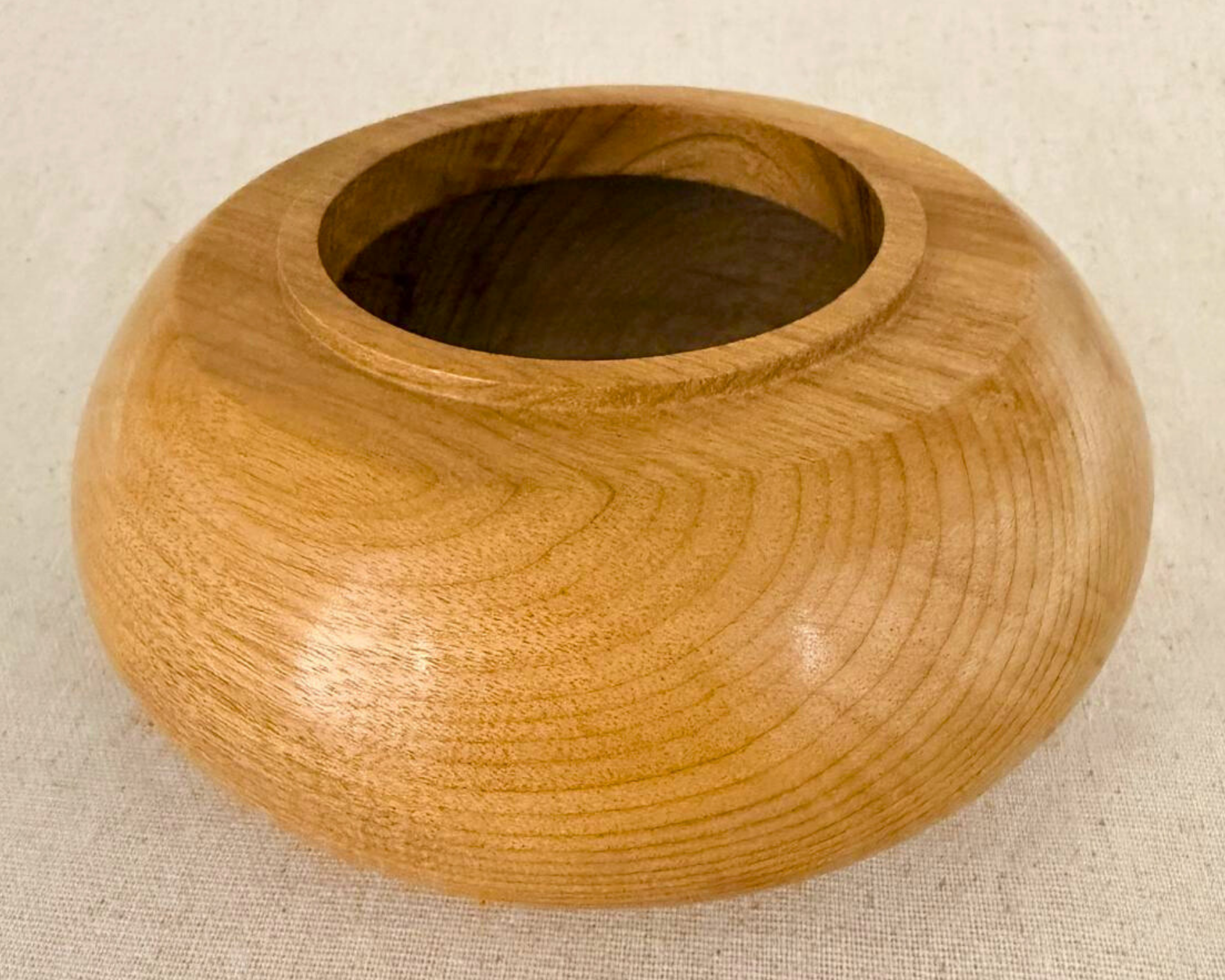Hand-turned myrtle vessel in three-quarter view with a low rounded body, raised opening, and soft golden wood tone.