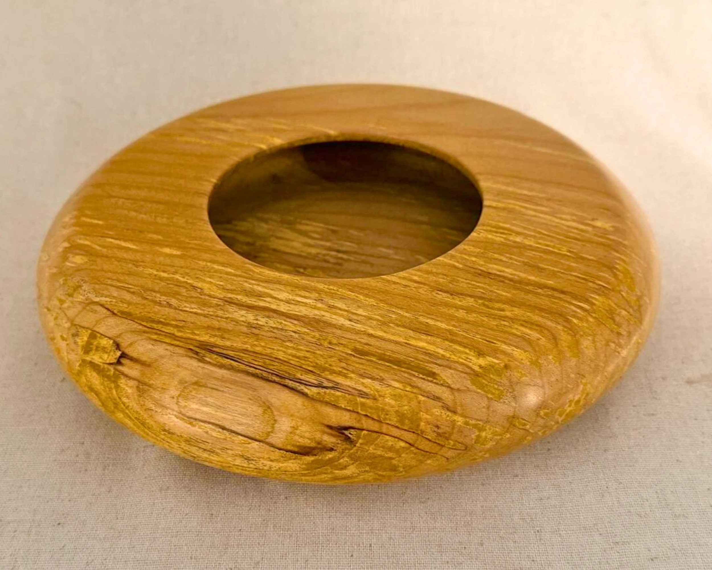 Angled top view of figured maple closed form vessel highlighting the circular opening and figure lines in the grain.