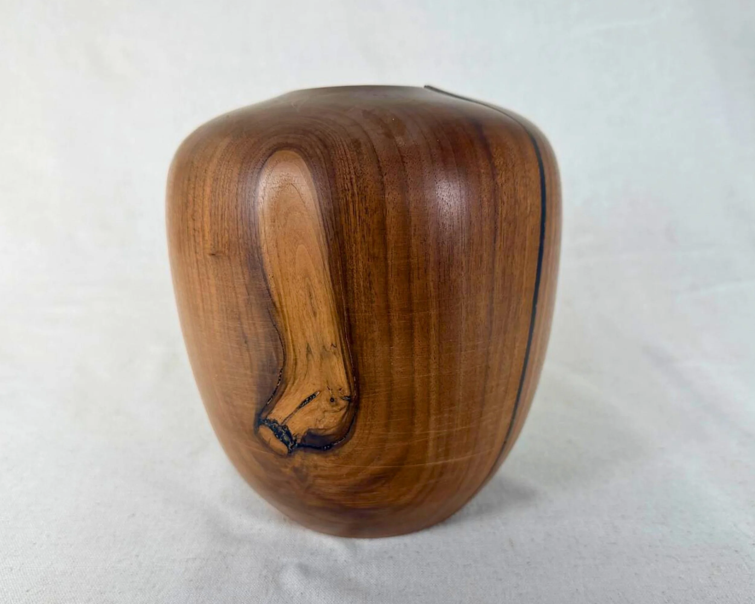 Walnut vessel front view showing unique grain feature area with black epoxy-filled voids near the base.