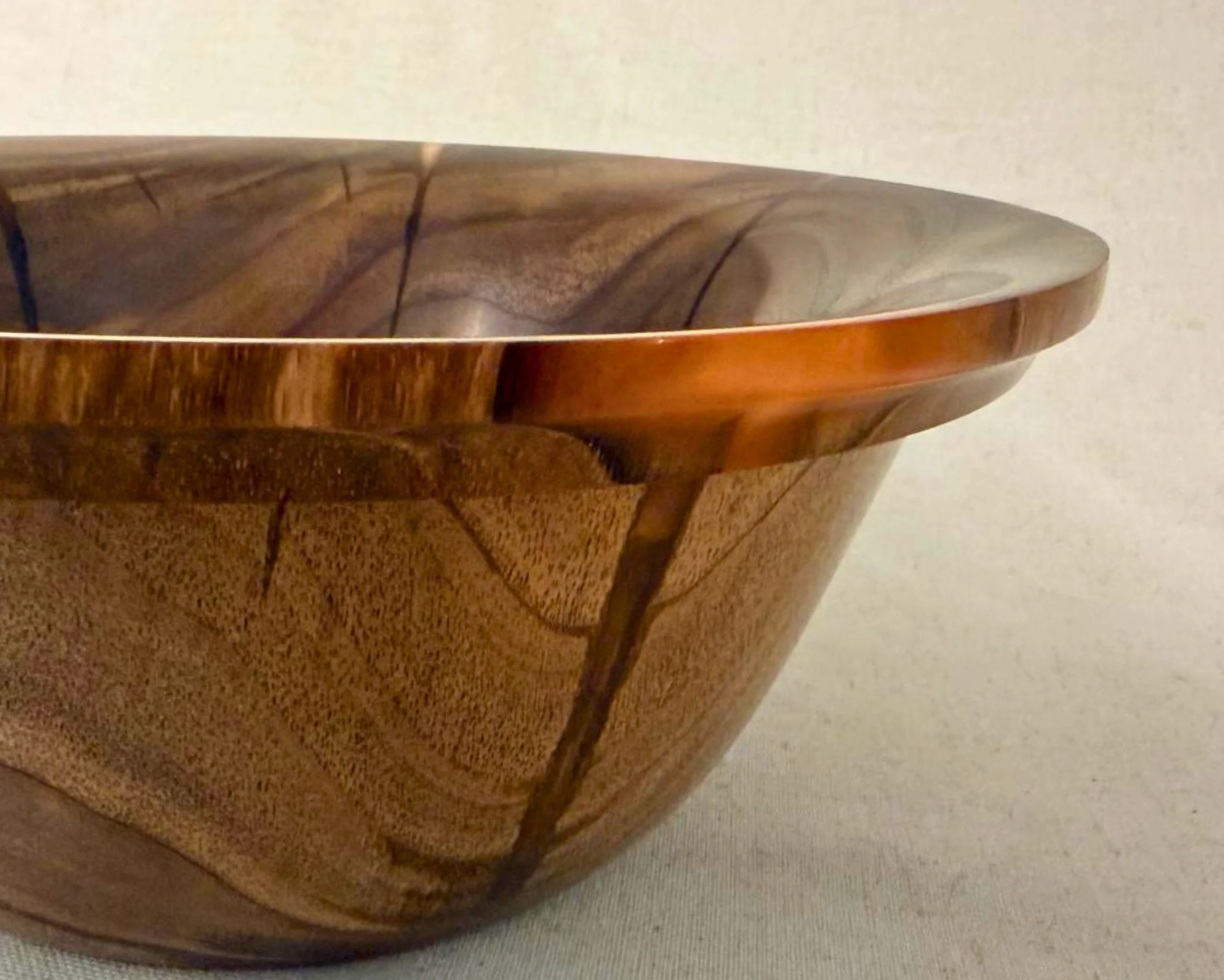 Close-up profile view showing red epoxy accent along the rim edge in claro walnut.