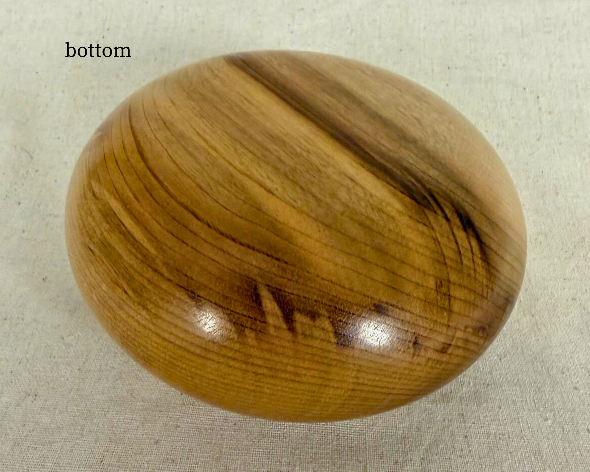 Bottom view of a hand-turned myrtle vessel showing rounded underside, flowing grain lines, and darker natural streaking.
