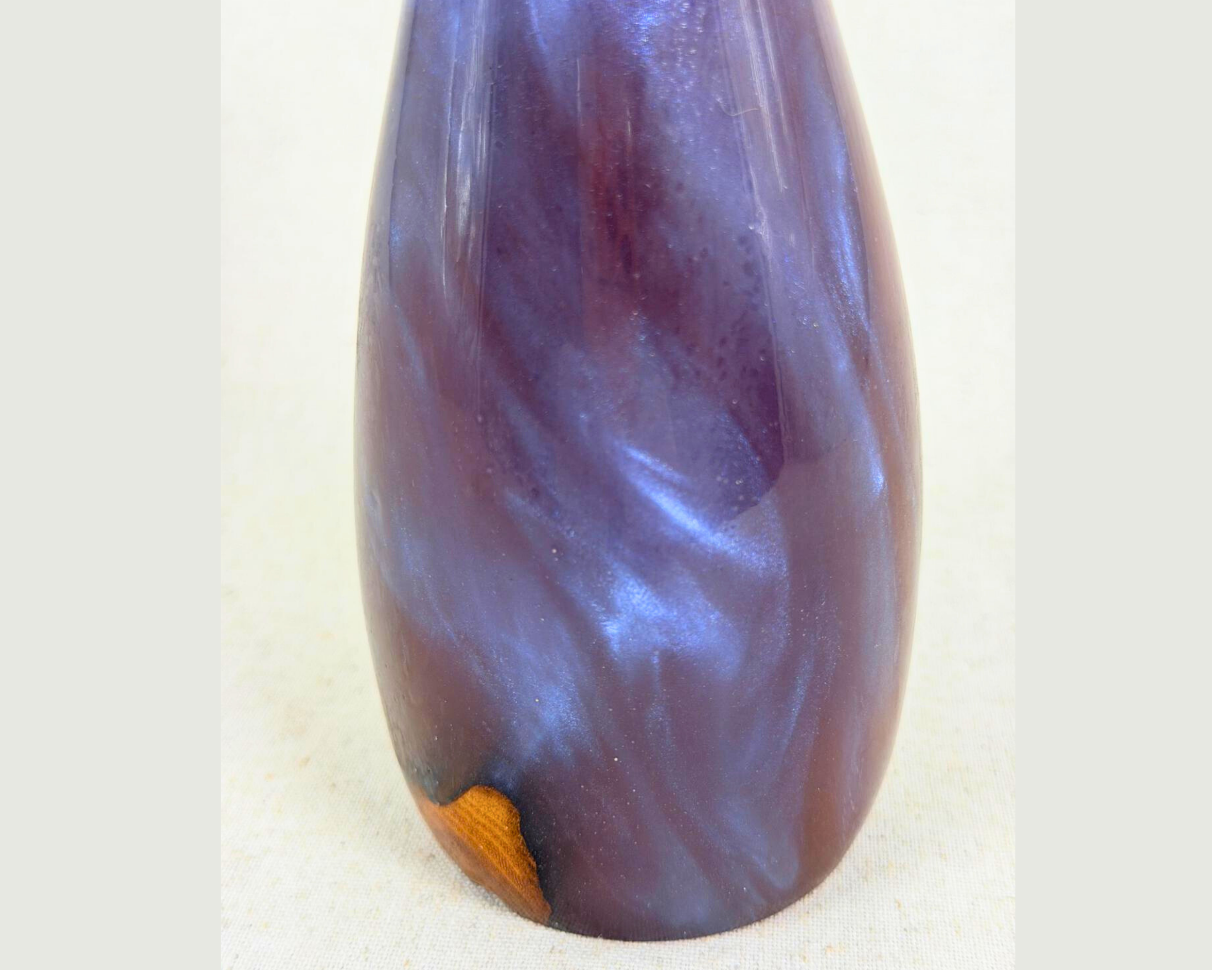 Close view of the sculpture’s lower body, showing swirling blue, red, yellow, and ochre epoxy with a small exposed driftwood area near the base.