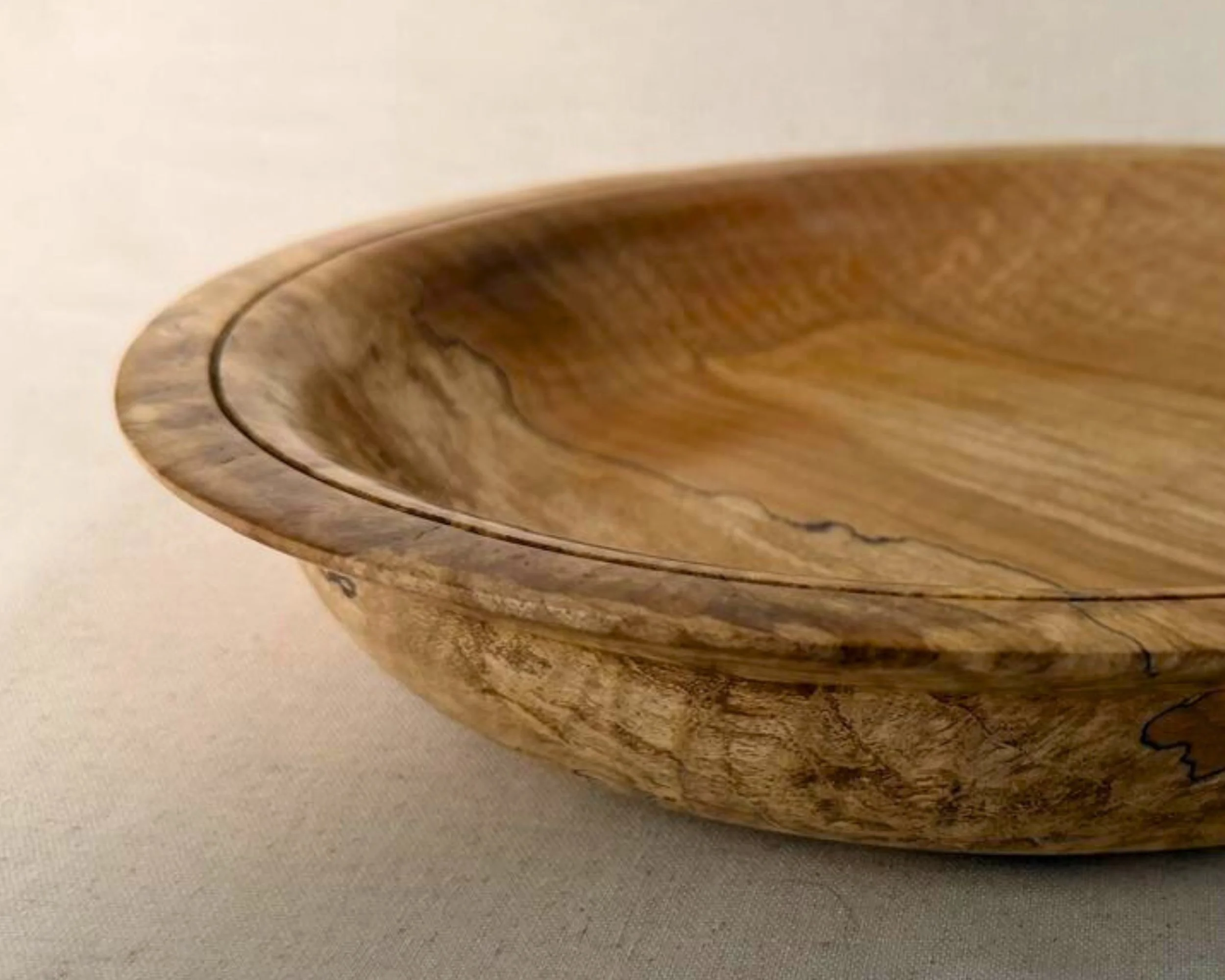 Close-up of the platter rim and interior, showing the thin circular groove detail, smooth turned wood, and subtle spalted figure.