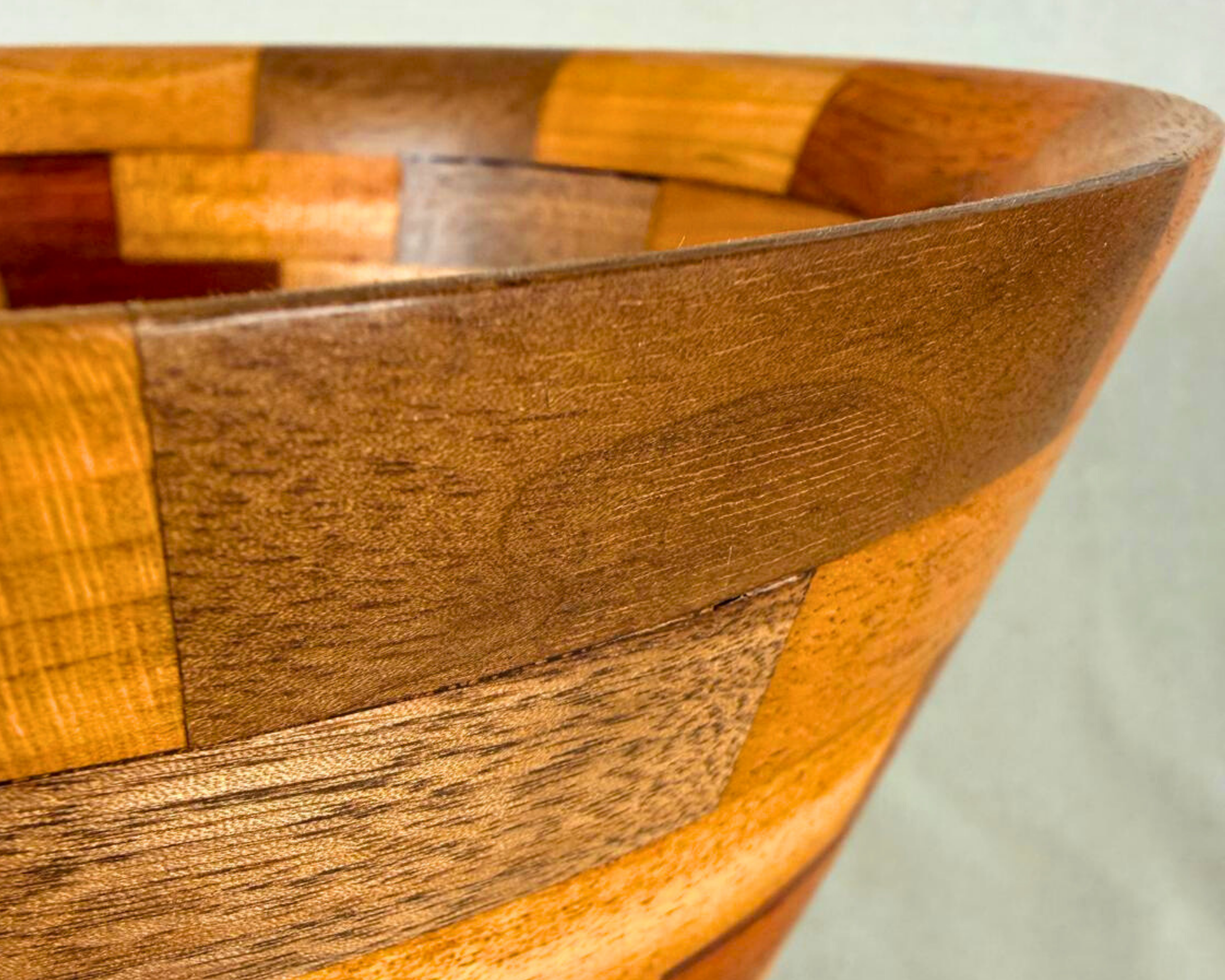 Close-up of the vessel rim showing the fine transition between walnut, maple, and adjacent segmented hardwood pieces along the upper edge.