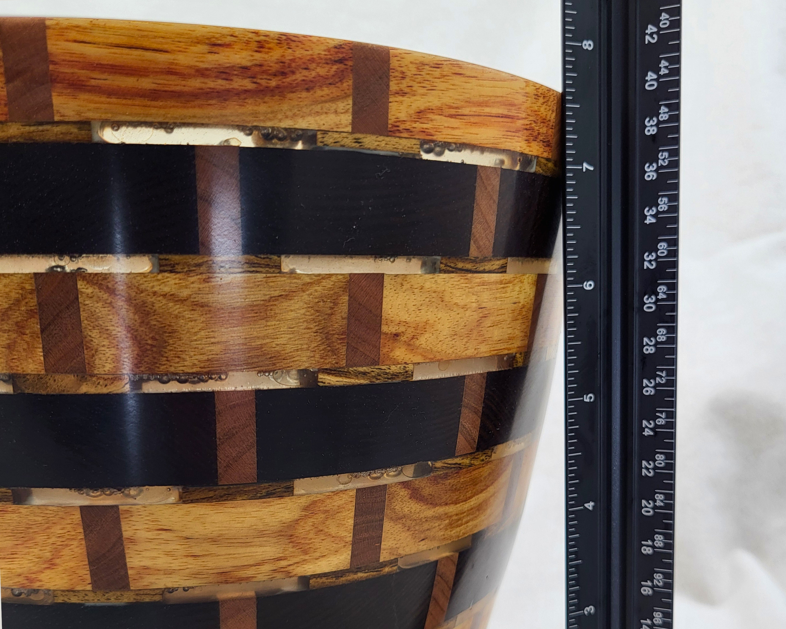 Scale reference for a hand-turned segmented vessel by Treverk Woodturning, 8 inches tall, shown beside a ruler with close detail of the clear resin set between canarywood, thermal ash, and cherry blocks. Sculptural wood art.