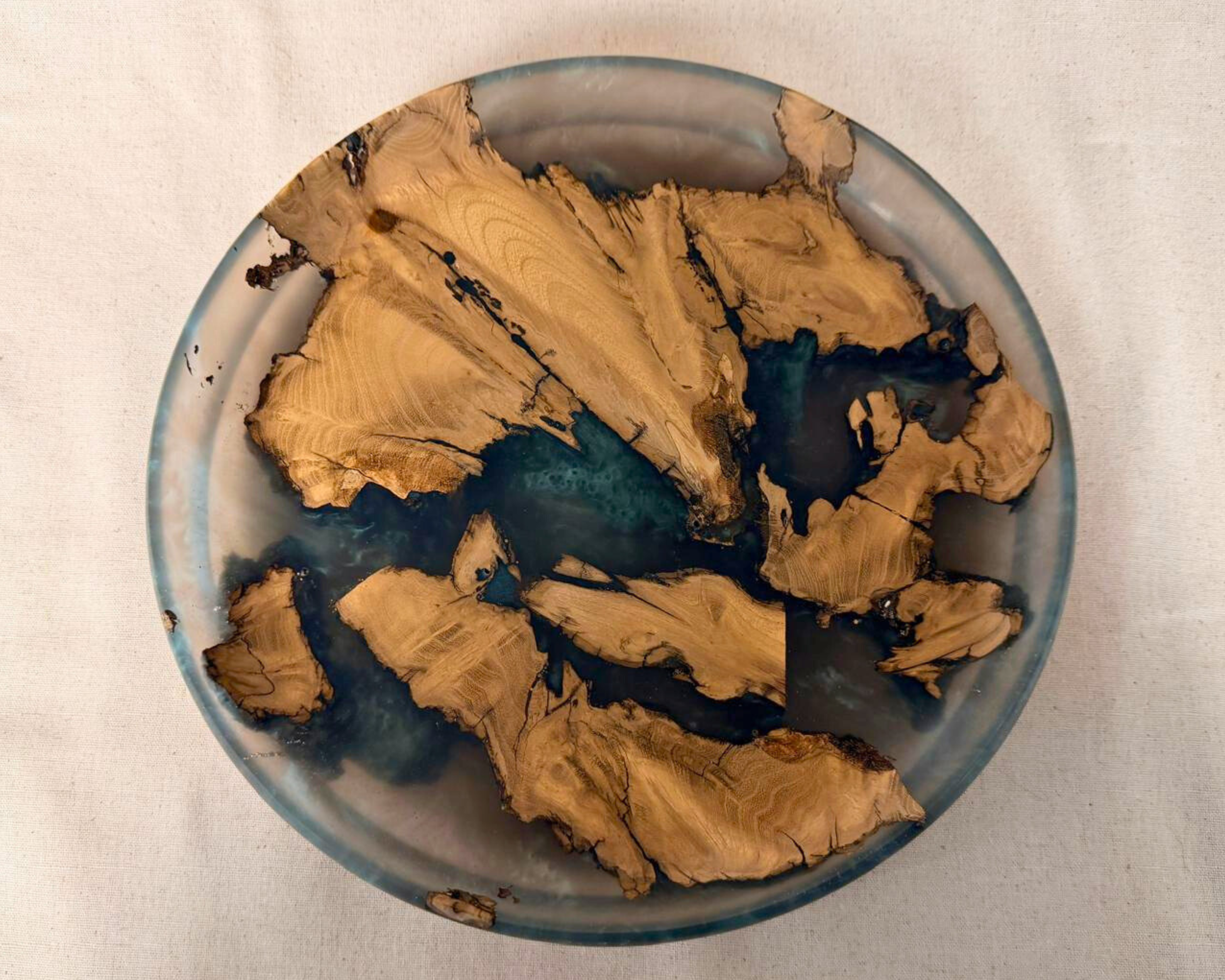 Top view of tree root epoxy platter with sweeping wood grain islands and deep blue charcoal resin channels.