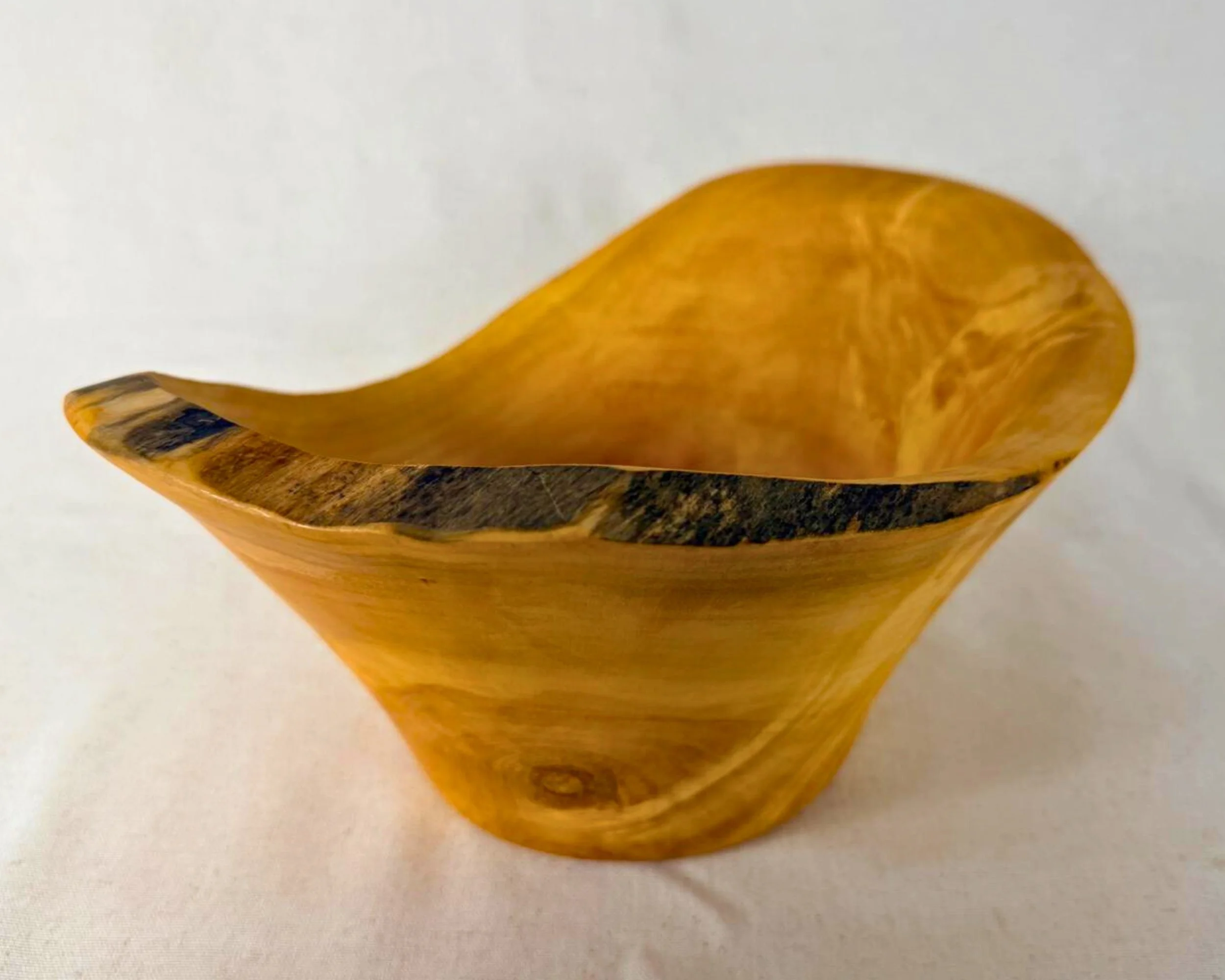 Angled view of reclaimed pine vessel showing asymmetric lip and dark natural edge band.