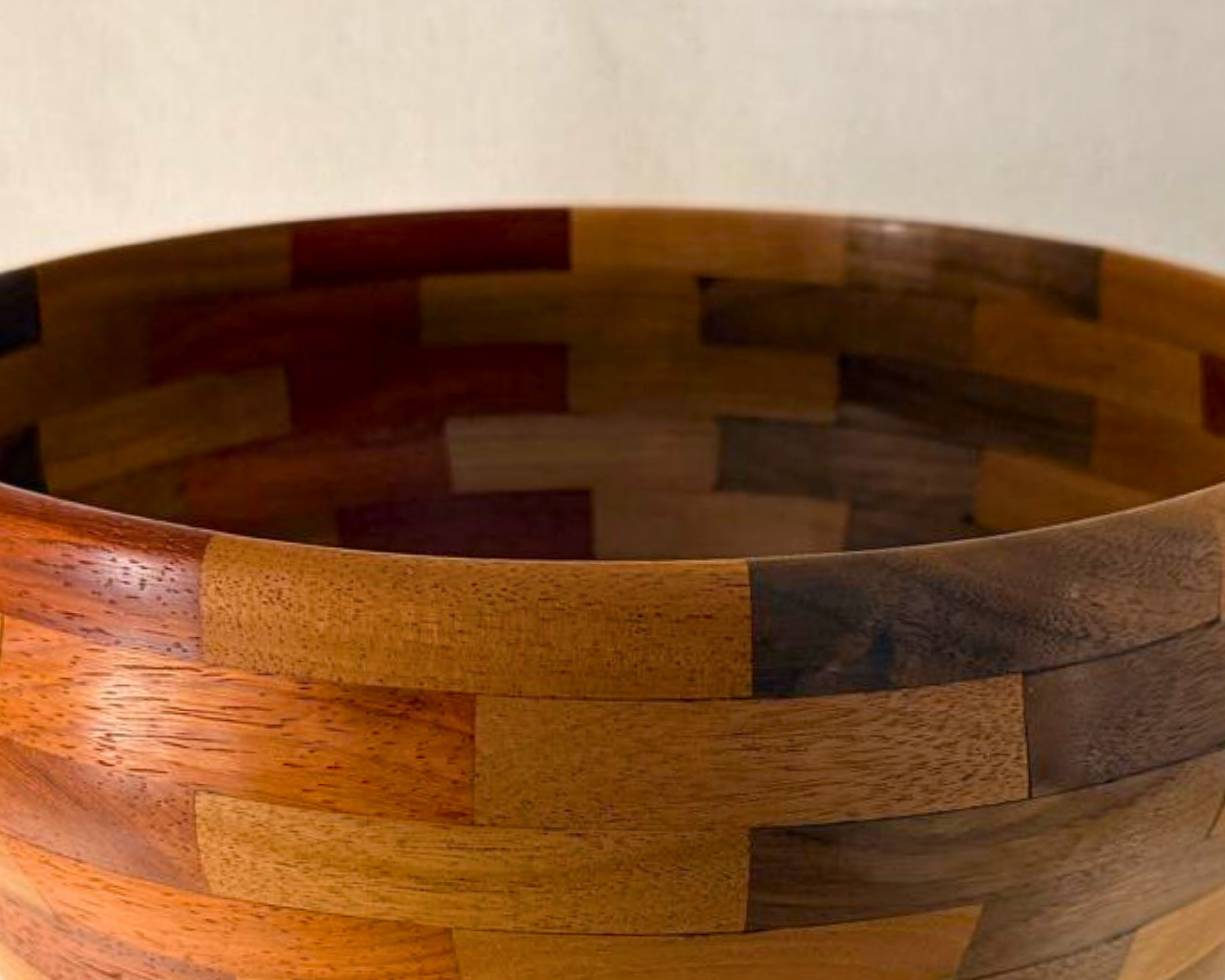 Close-up of segmented vessel showing brickwork joinery and contrasting walnut padauk and maple grain.
