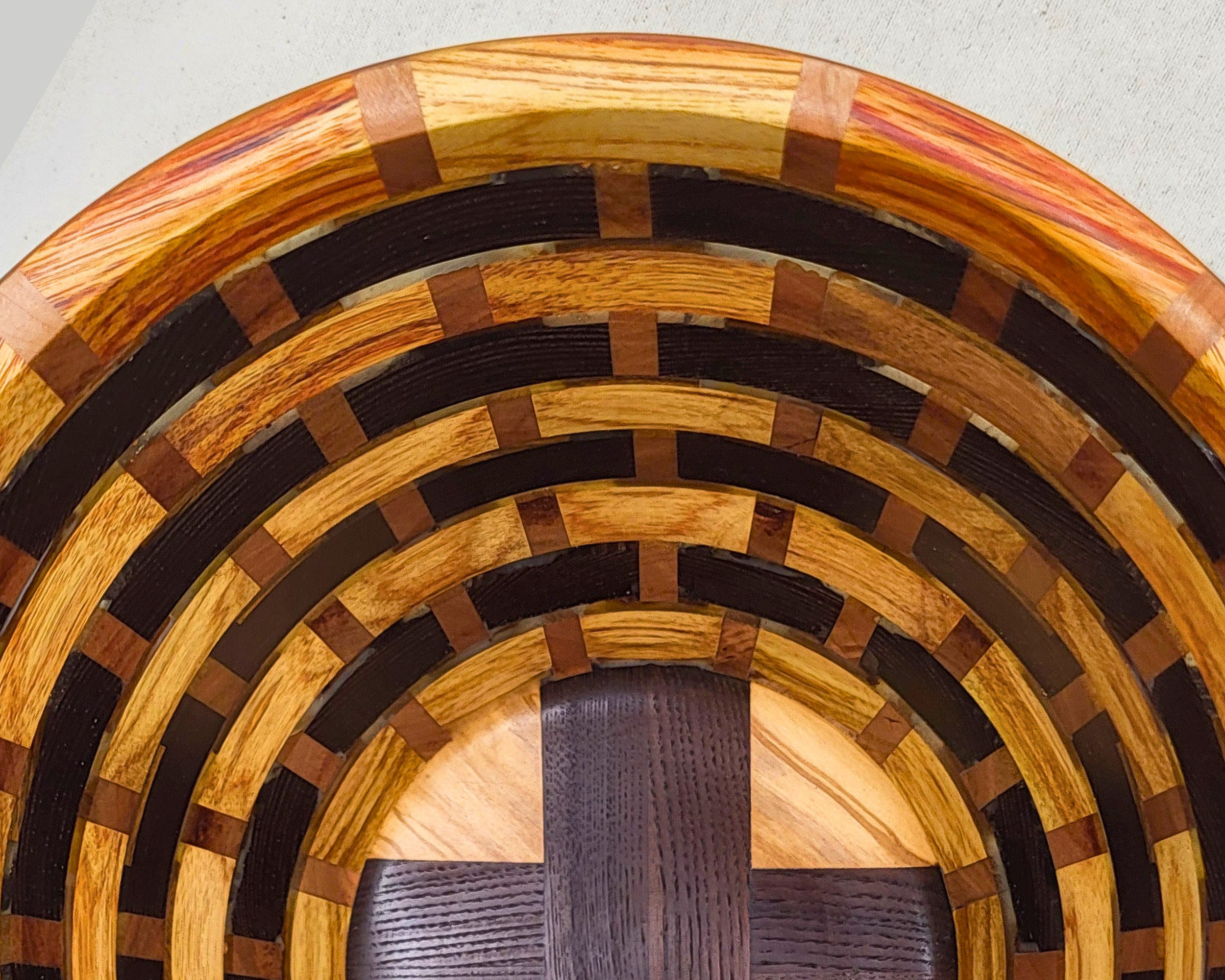 Close interior detail of a hand-turned canarywood, thermal ash, and cherry segmented vessel by Treverk Woodturning, revealing the brick coursing of the rings and the textured grain of thermal-treated ash at the base. Sculptural wood art.