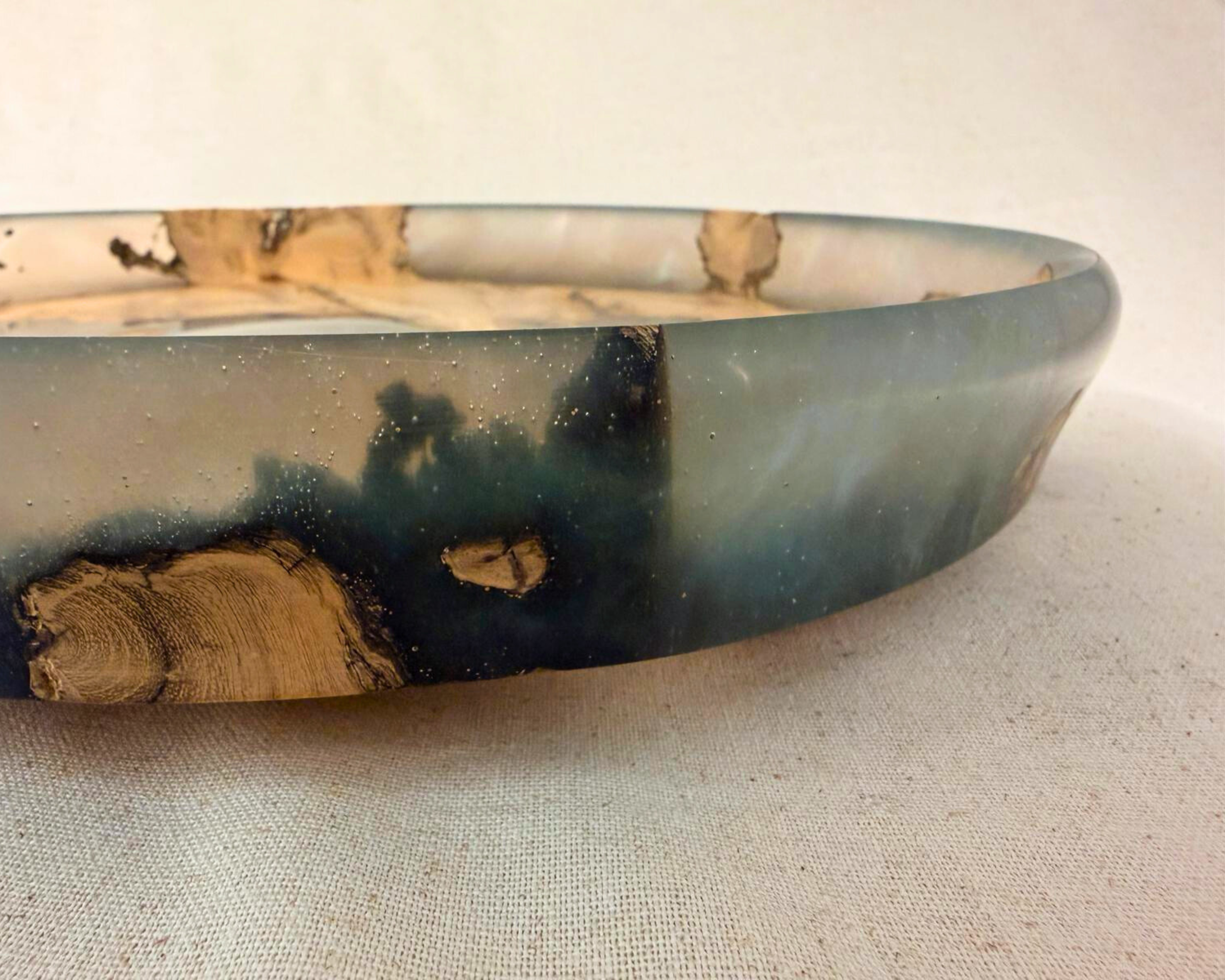 Rim detail of epoxy platter showing translucent resin edge with small natural wood inclusions.