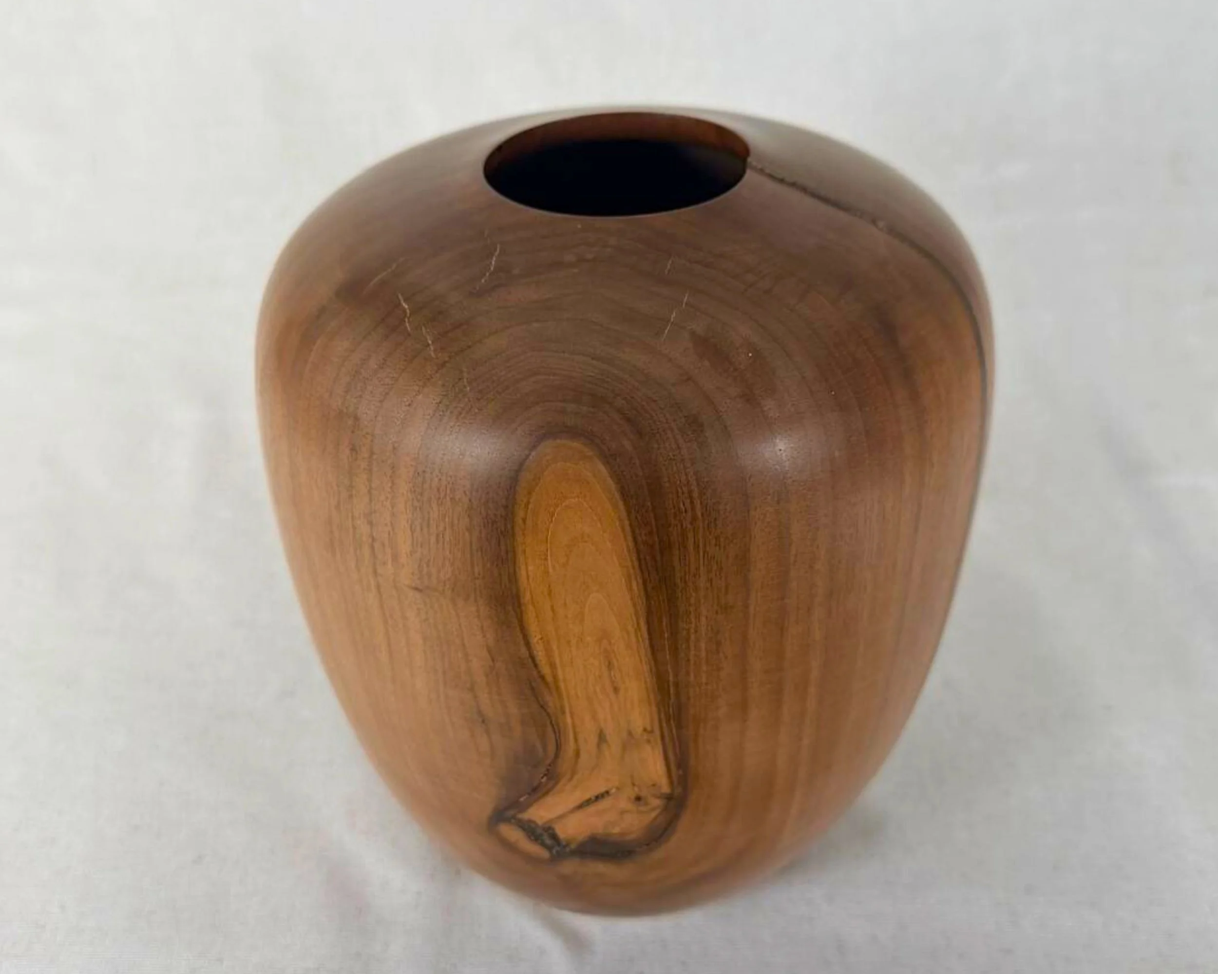 Slightly top-down view of walnut vessel showing rimless opening and prominent grain feature with black epoxy accents.